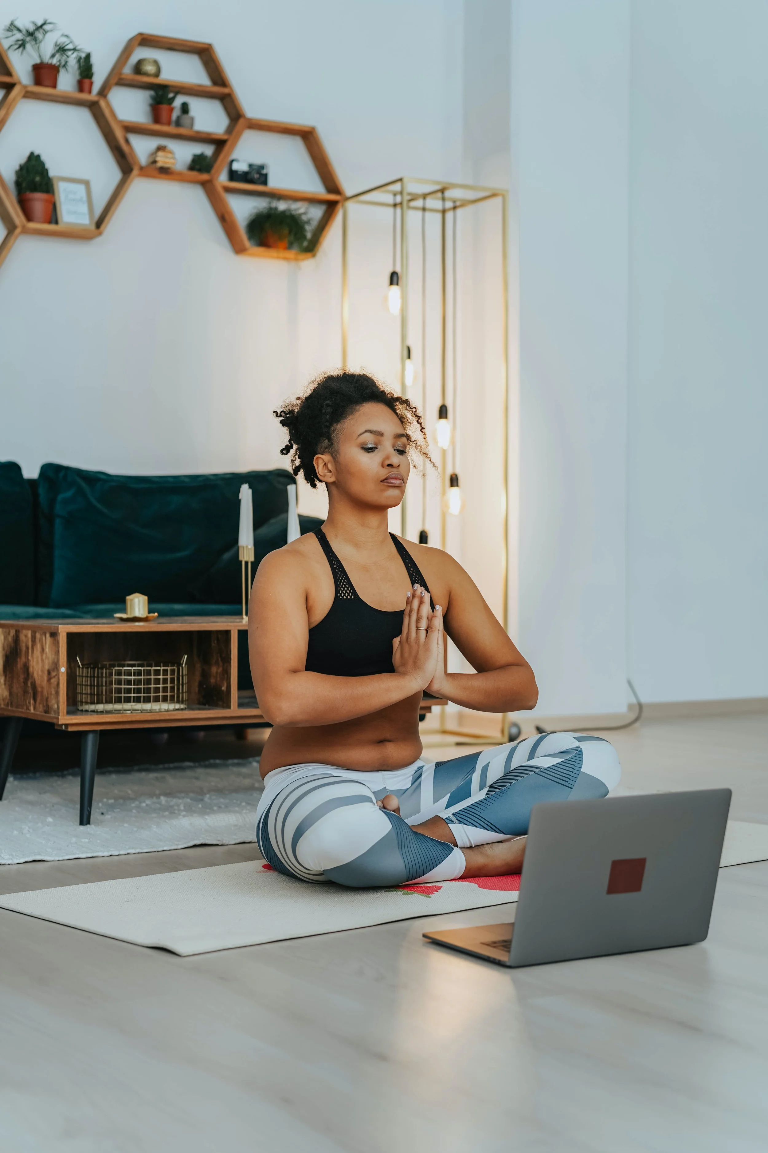 Woman doing yoga from her house using her laptop, during the pandemic lockdown.