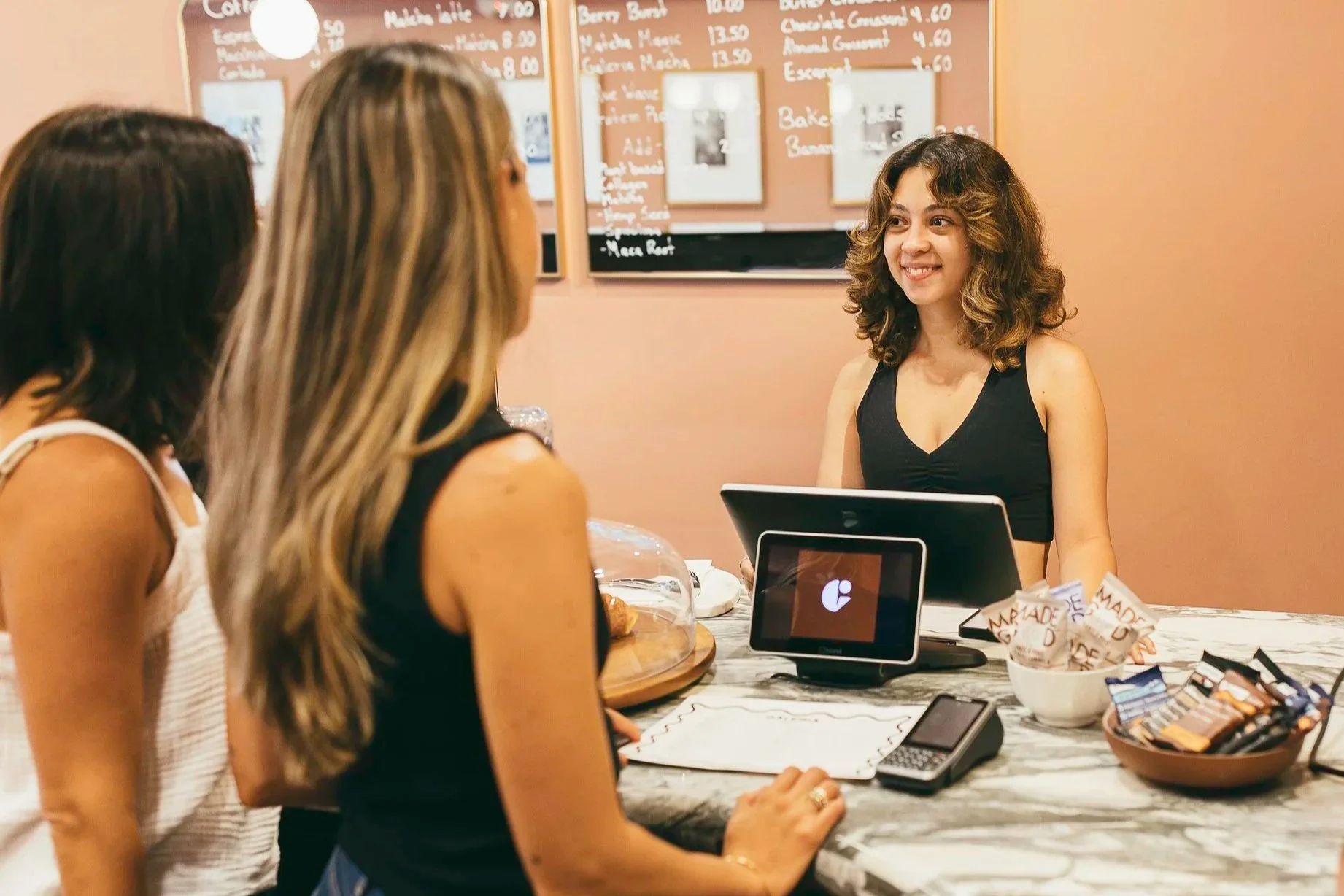 Front desk staff member helping two fitness studio clients checkout