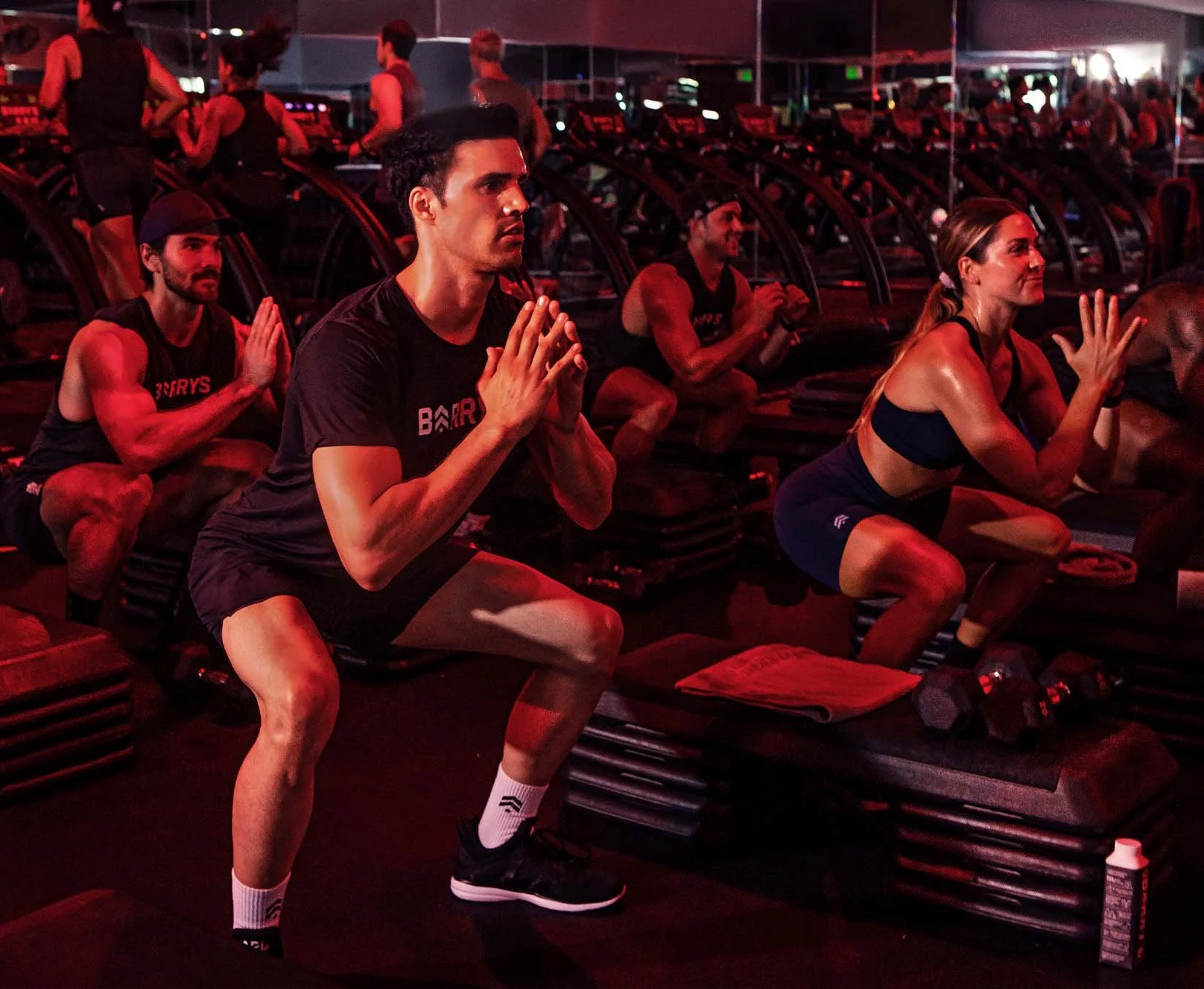 People doing squats during a group workout session at Barry's