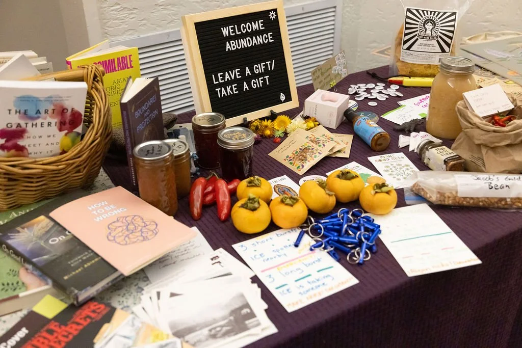 abundance table with books, fruit, whistles, and seeds offered by event attendees