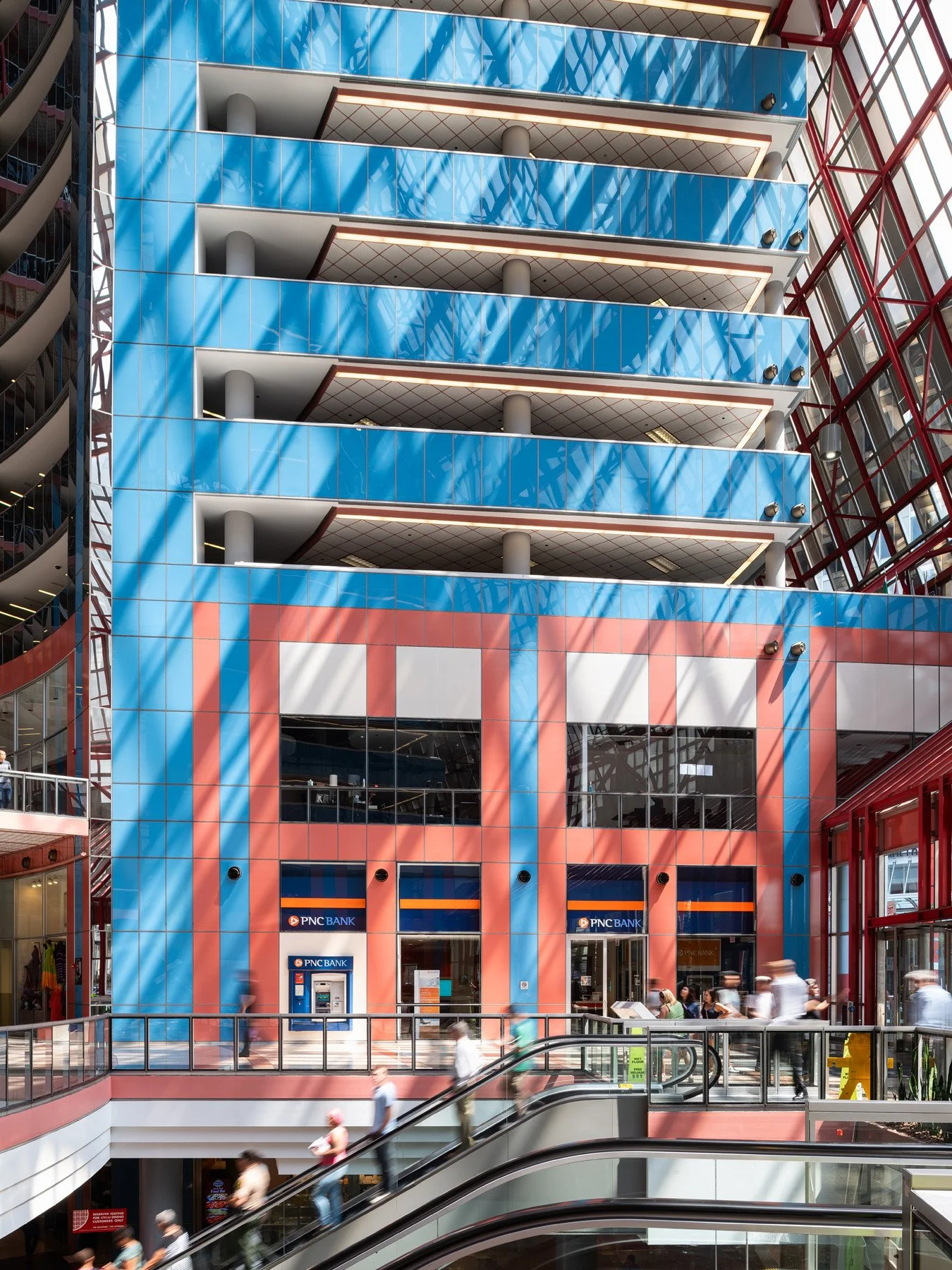 James R. Thompson Center atrium core, sunlight raking across salmon and sky blue panels above PNC Bank, Chicago - postmodern color scheme