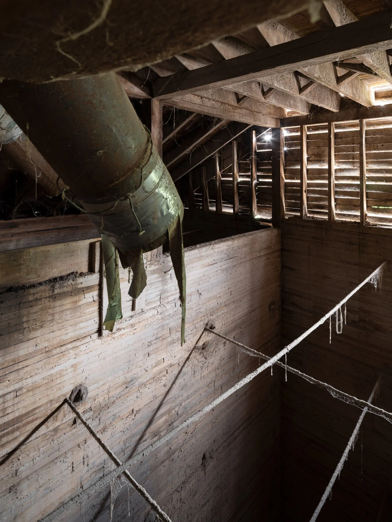 Millstadt Mill interior of the cribbed timber grain elevator, stacked-plank walls lit through slatted openings - architectural photographer St. Louis Missouri