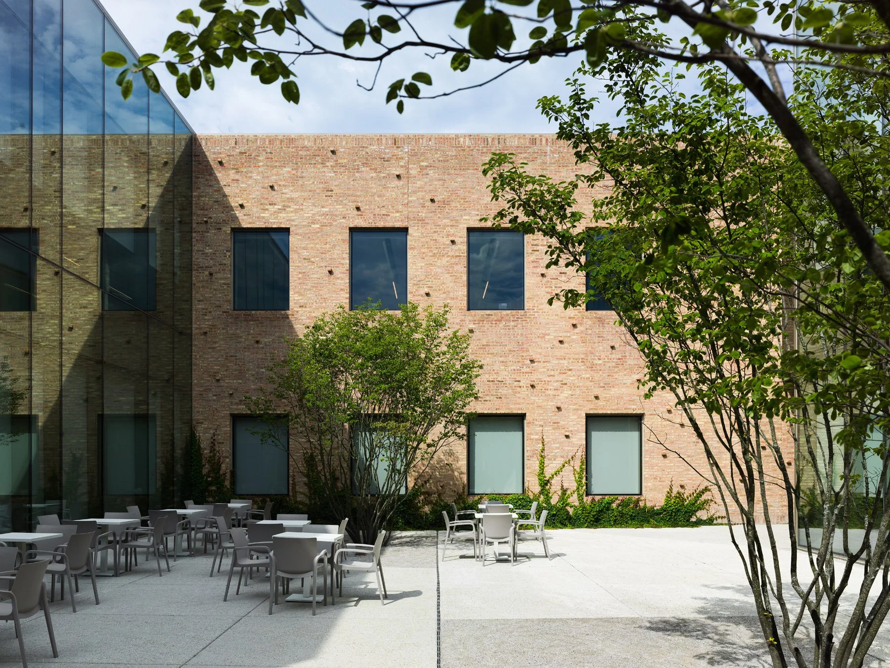 Chicago Park District HQ interior courtyard cafe terrace with seating, brick facade, and multi-stem trees - architectural photographer Chicago Illinois