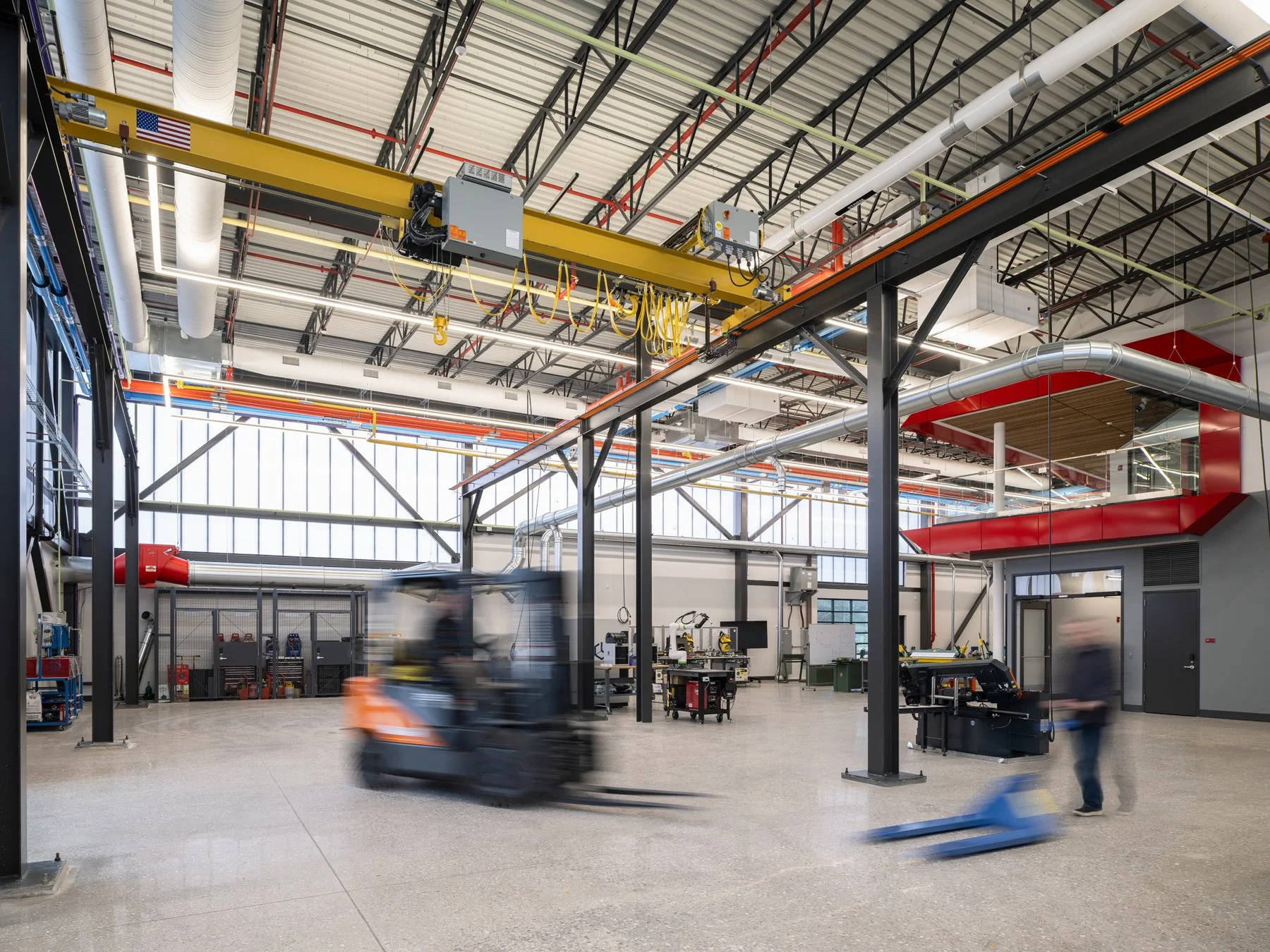 Regional Workforce Innovation Center high-bay fabrication shop with a yellow overhead bridge crane and a forklift crossing the polished floor, Wentzville, Missouri, by JEMA - architectural photographer St. Louis Missouri