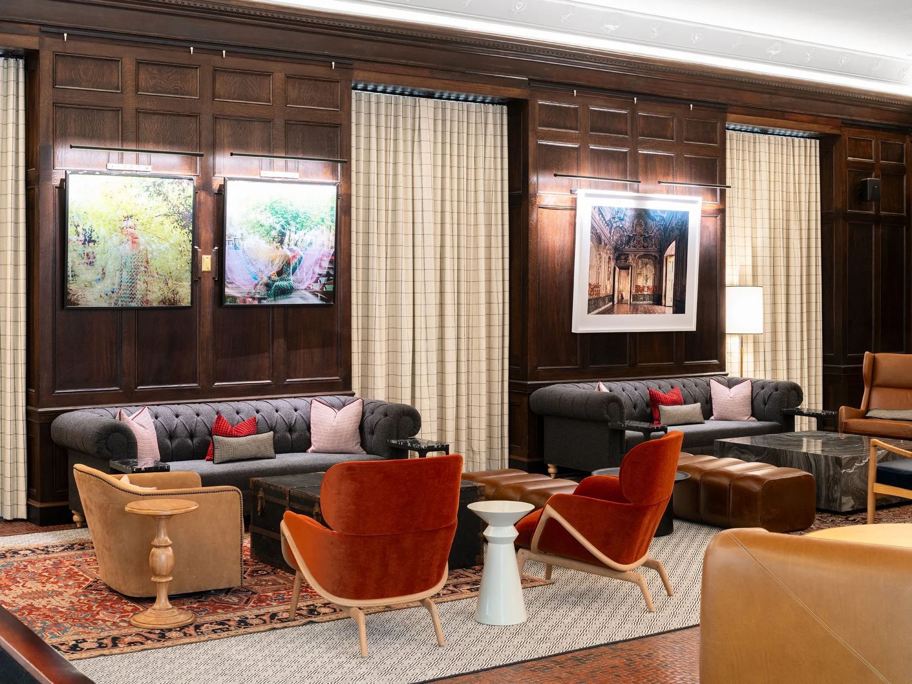 21c Museum Hotel interior lounge with charcoal tufted chesterfield sofas and rust velvet chairs against oak paneling hung with contemporary photography, by Perfido Weiskopf Wagstaff + Goettel and Hufft - architectural photographer St. Louis Missouri