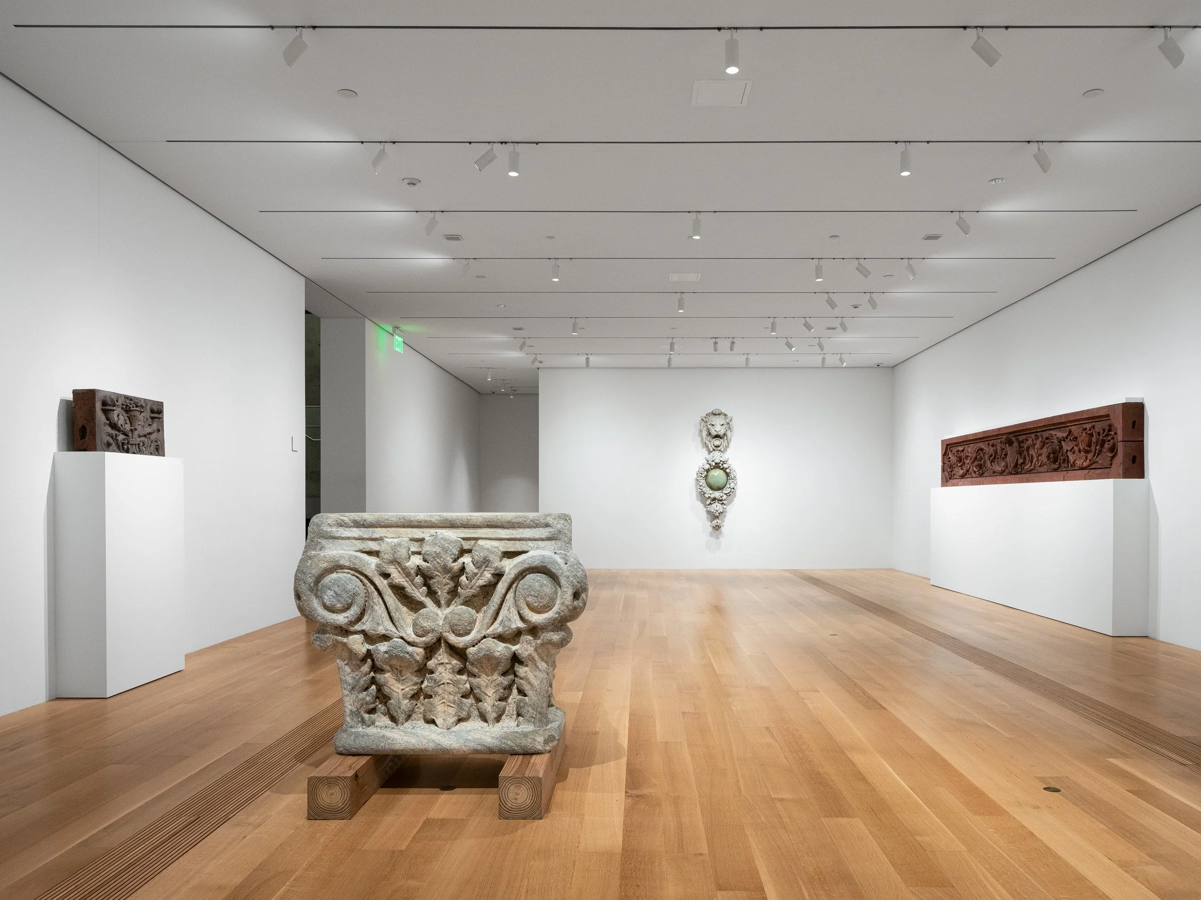 Pulitzer Arts Foundation interior gallery with white oak floors and track lighting displaying a large carved stone capital and architectural ornament fragments, by Tadao Ando, St. Louis Missouri - architectural photographer St. Louis Missouri