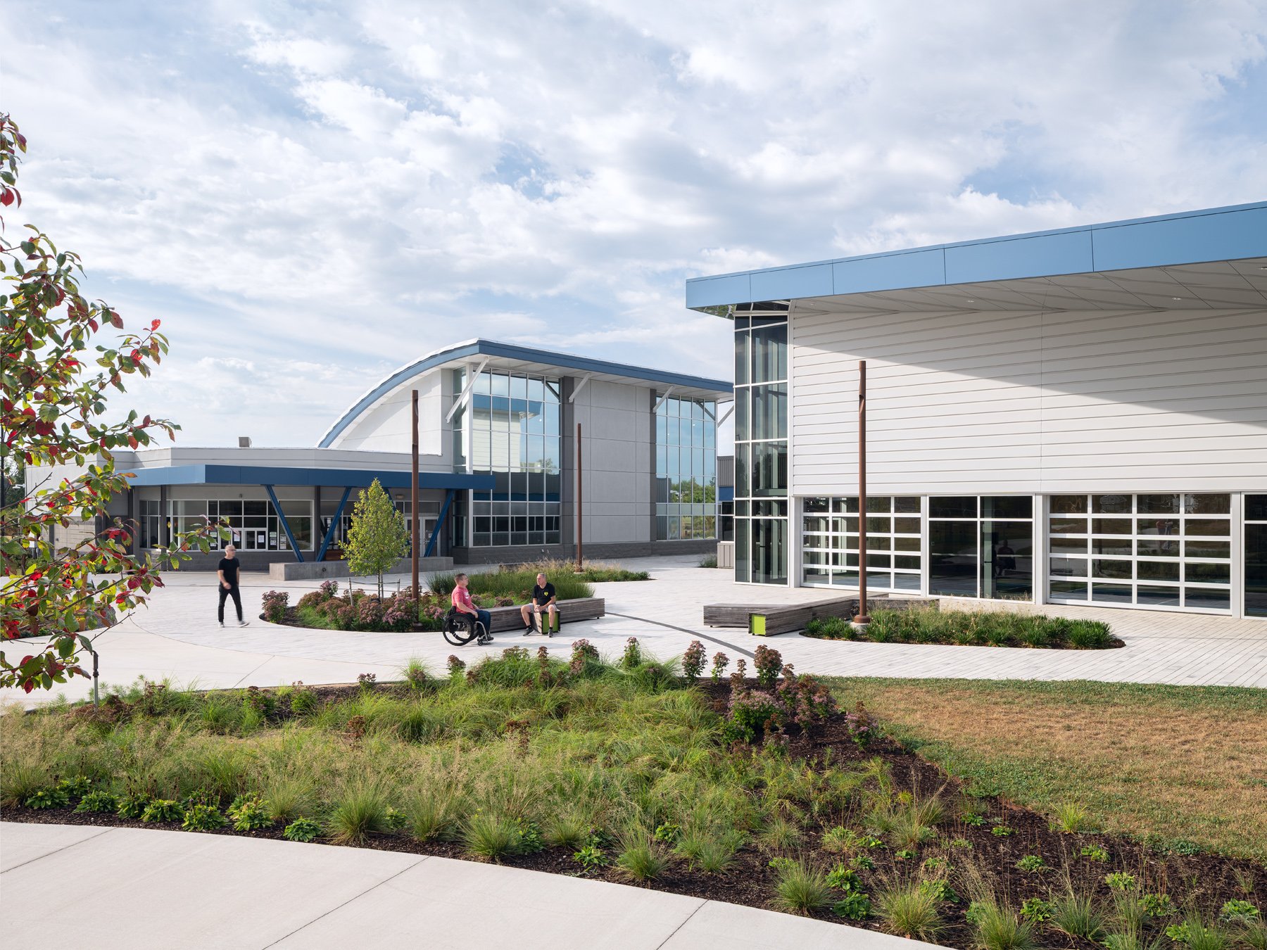Kinetic Park exterior plaza with curved-roof wing and angular blue entry canopy, by JEMA - architectural photographer St. Louis Missouri