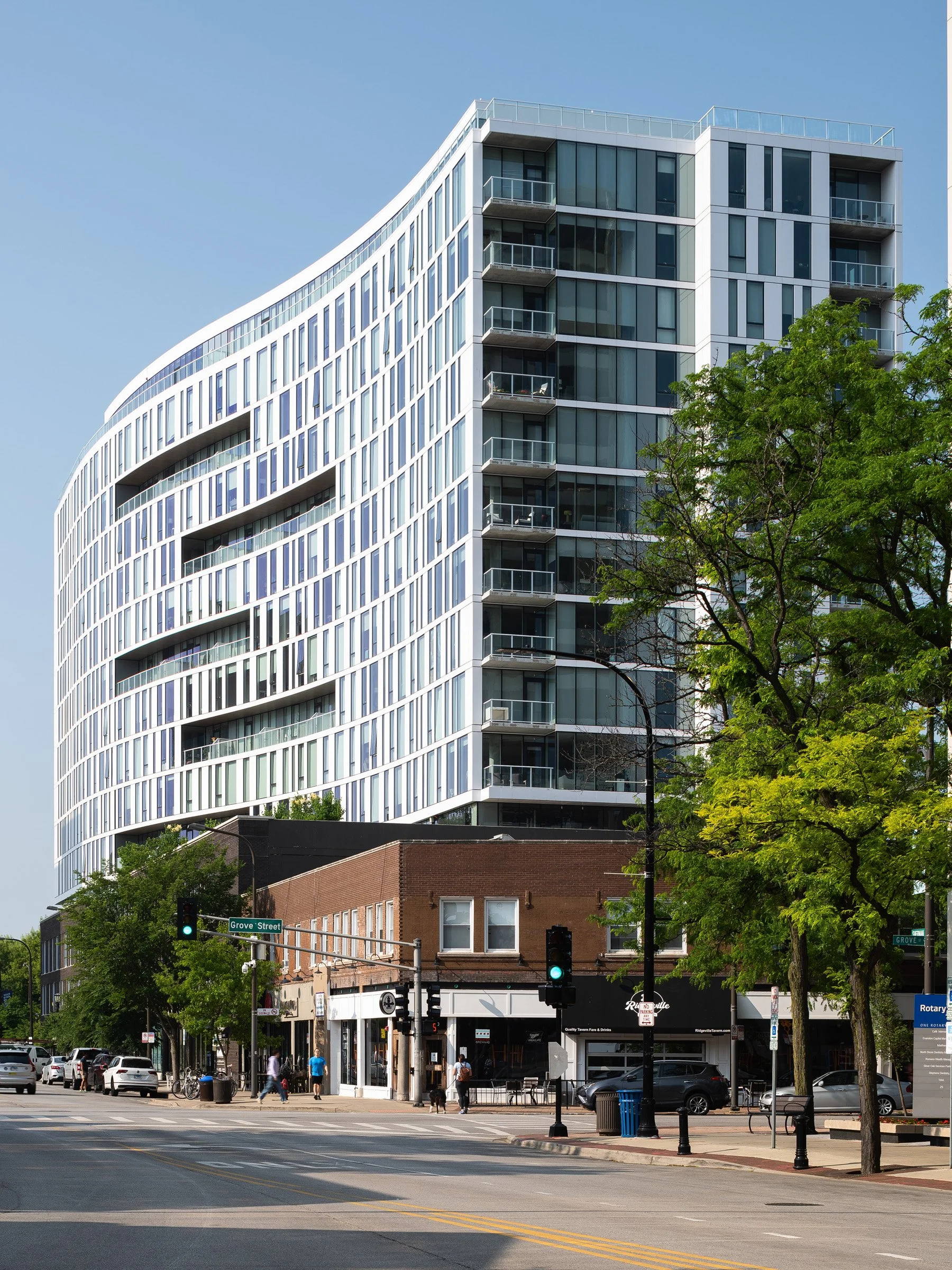 Albion Evanston exterior from Grove Street showing the shallow S-curve of the glass facade and stacked balconies, by Hartshorne Plunkard Architecture, Evanston Illinois - architectural photographer Chicago Illinois