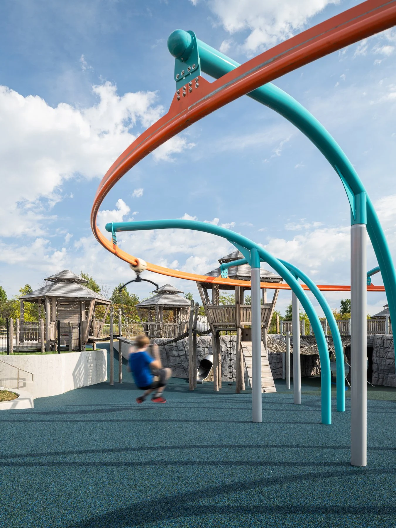 Kinetic Park child riding the looping track glider above the play towers, landscape by DG2 Design - architectural photographer St. Louis Missouri