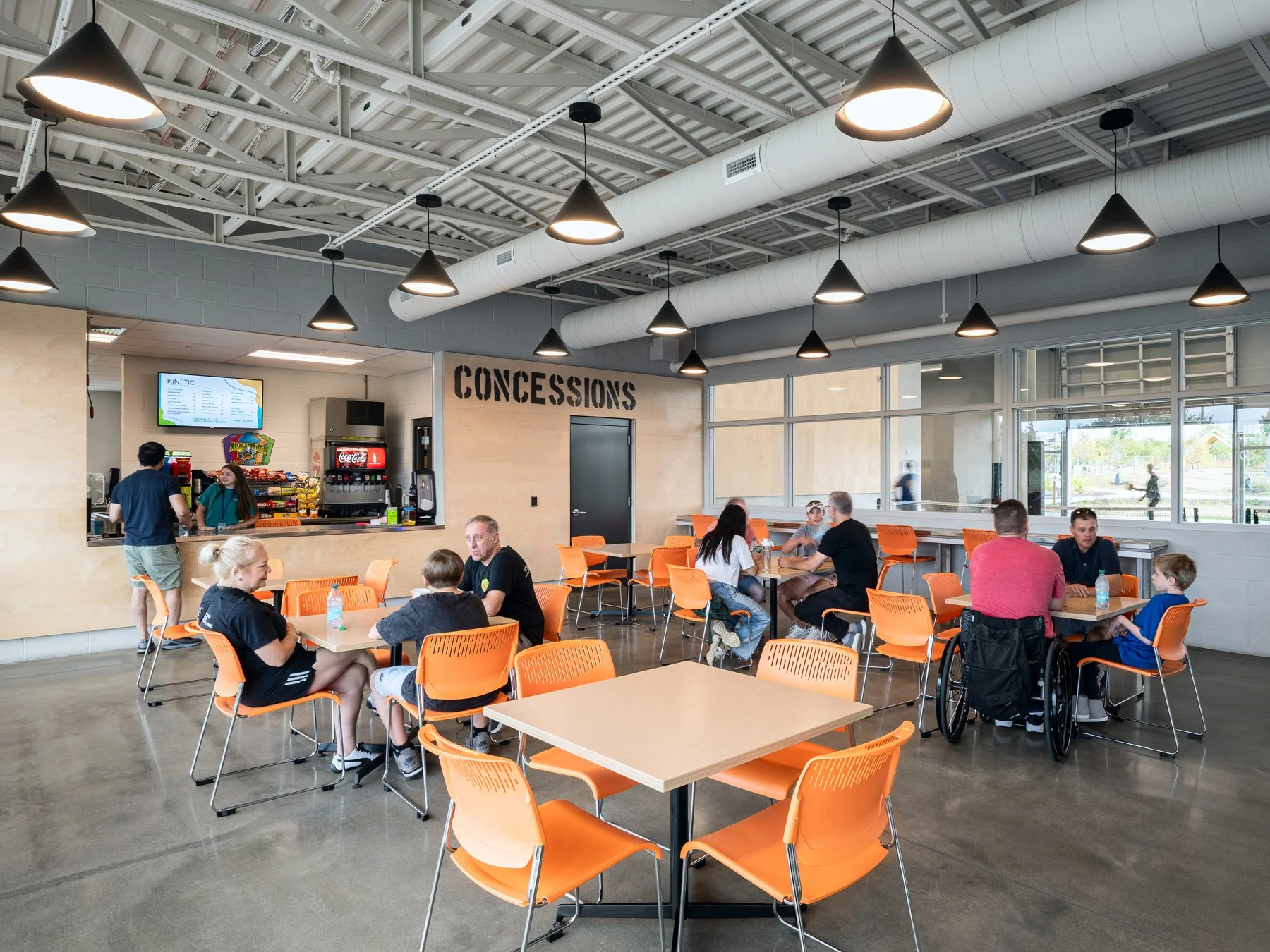 Kinetic Park interior concessions cafe with orange seating and pendant lights, by JEMA - architectural photographer St. Louis Missouri