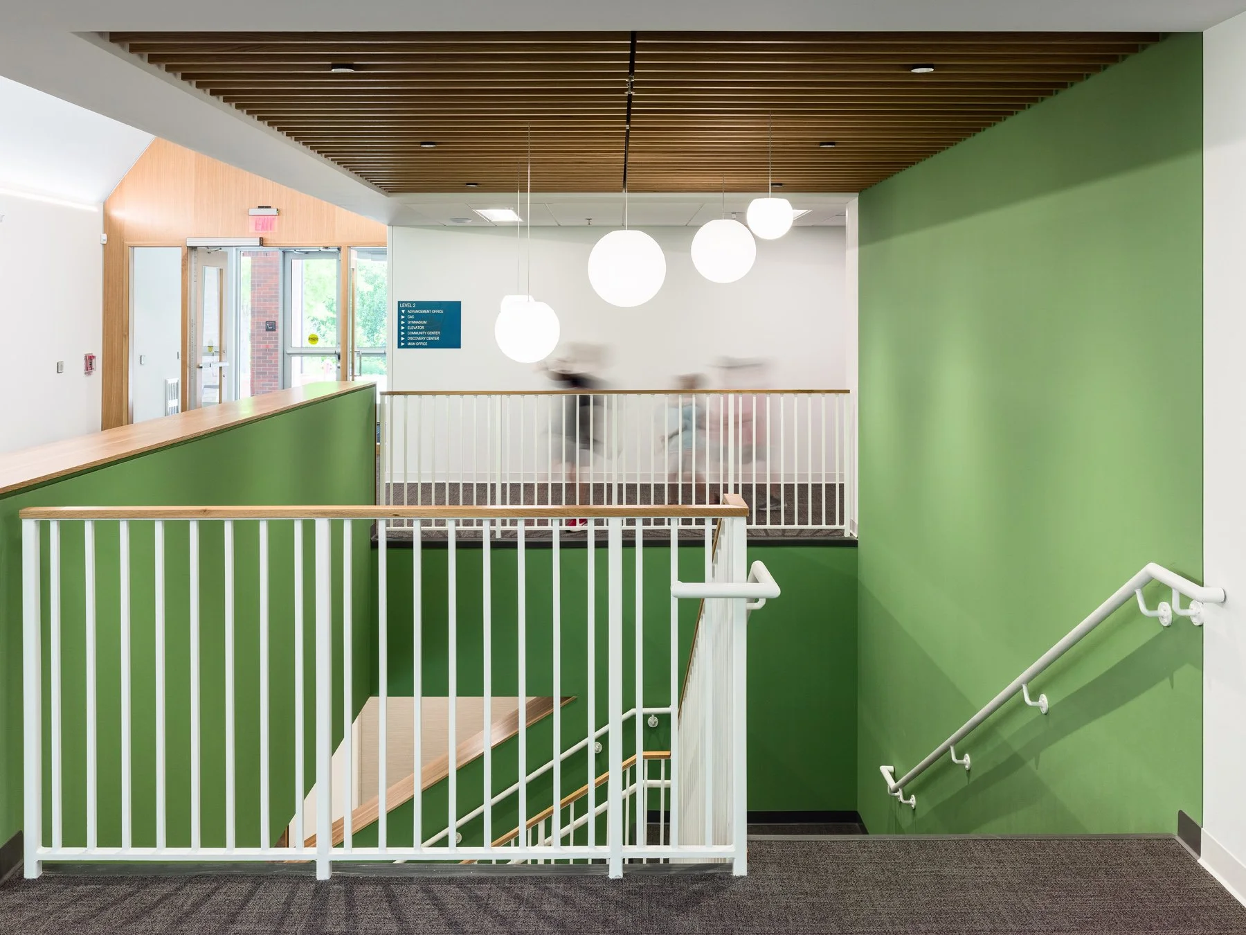 Broughton STEAM Center interior stair landing with green walls and a wood slat ceiling, by Christner - architectural photographer St. Louis Missouri