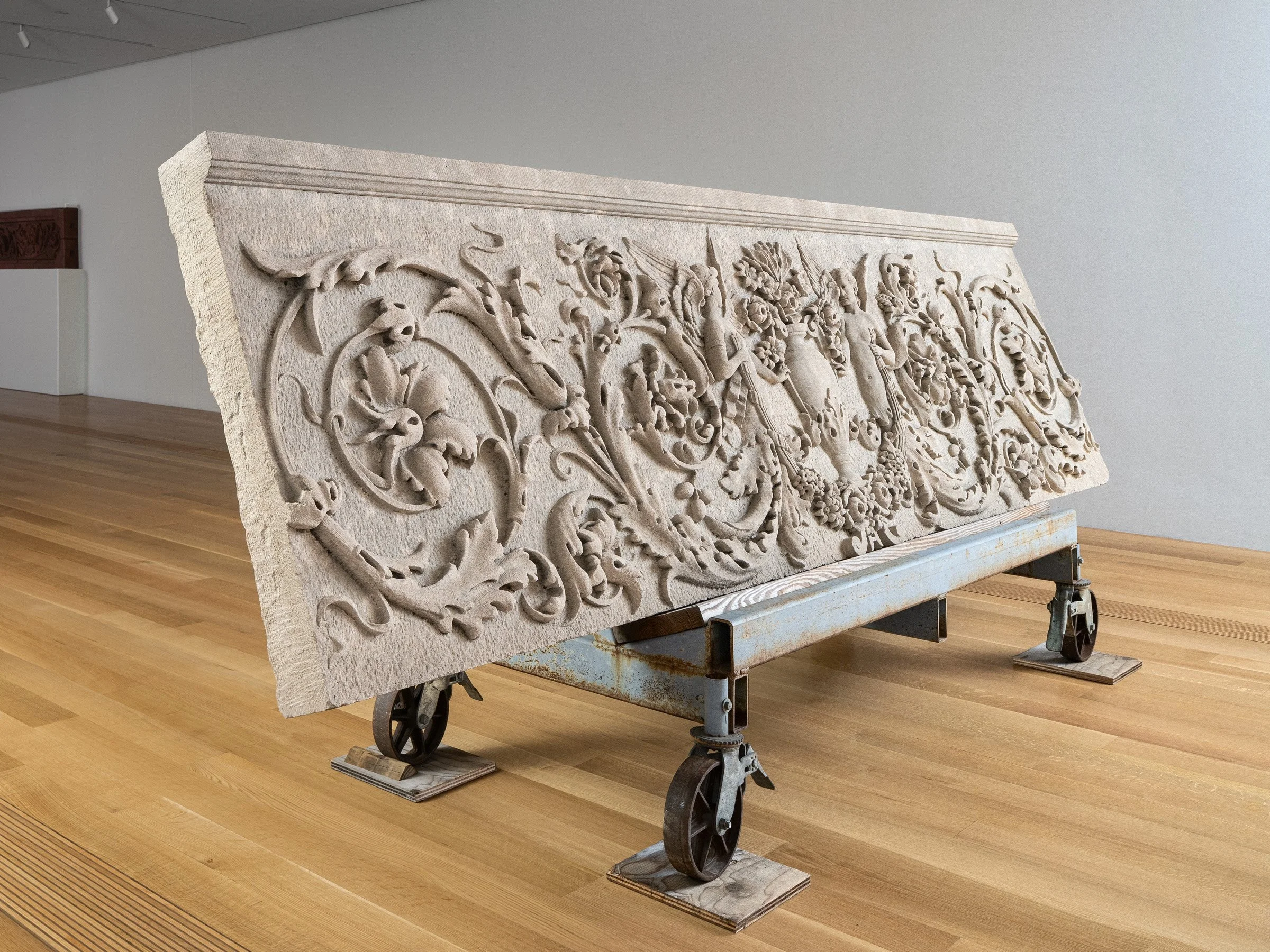 Pulitzer Arts Foundation interior gallery showing a carved limestone frieze with foliate scrollwork and a putto displayed on an industrial rolling cart, by Tadao Ando, St. Louis Missouri - architectural photographer St. Louis Missouri