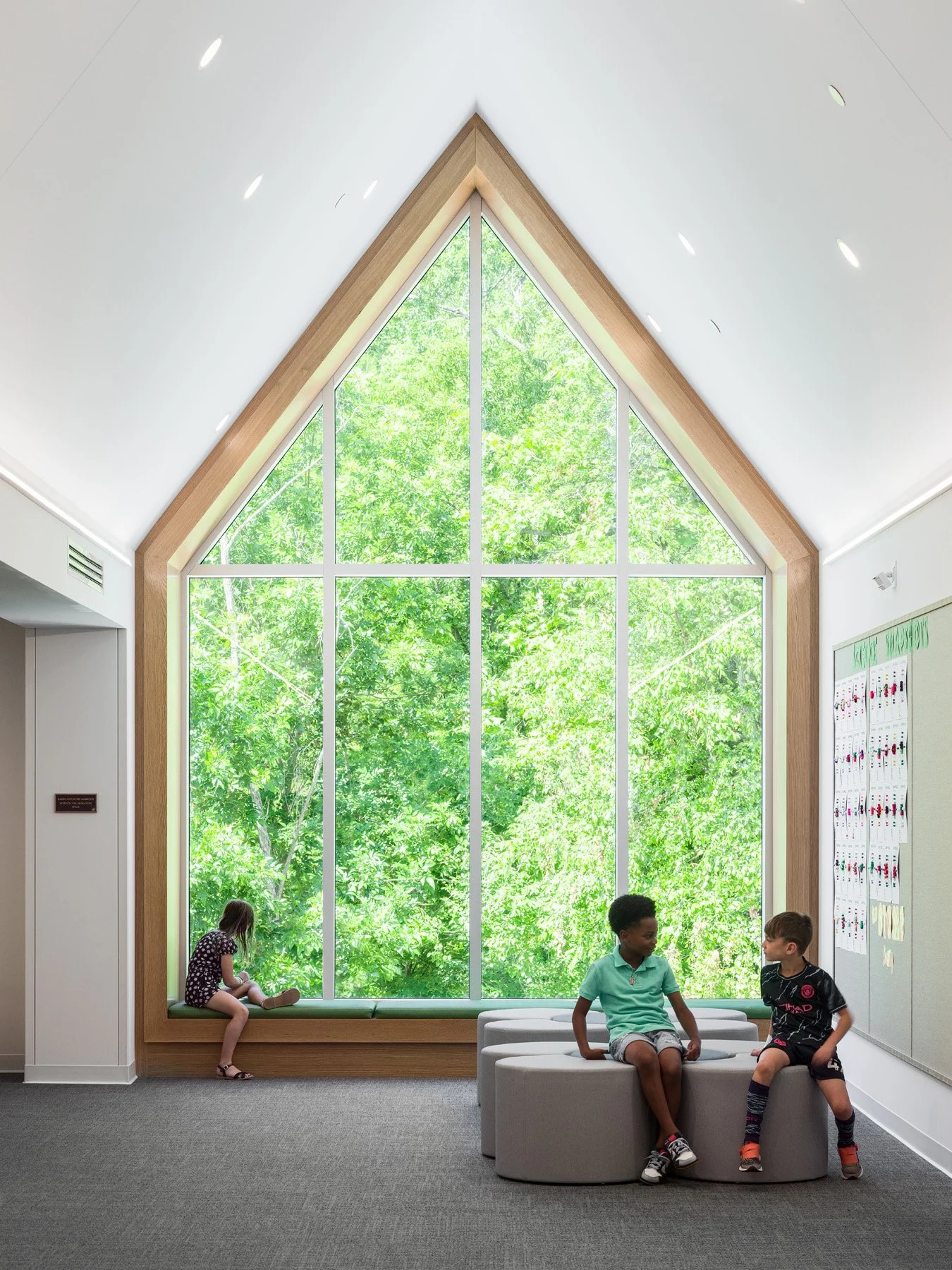 Broughton STEAM Center interior peaked window framed in white oak above a bench seat, by Christner - architectural photographer St. Louis Missouri