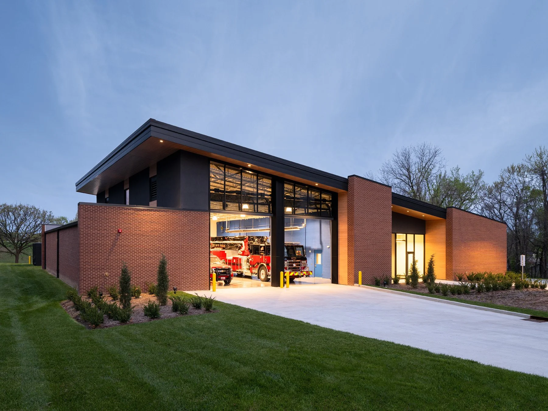 St. Charles fire station dusk exterior with a lit open apparatus bay, by JEMA, St. Charles Missouri - architectural photographer St. Louis Missouri