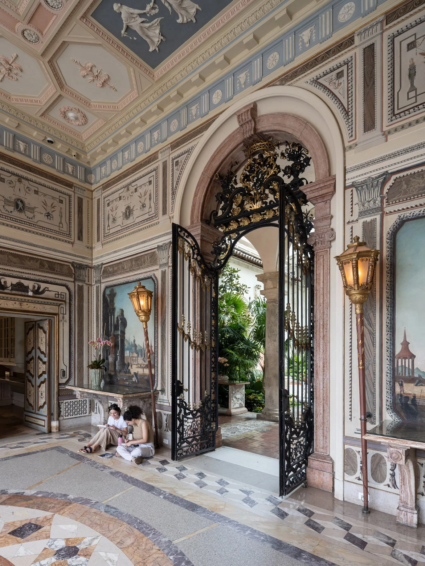Vizcaya Museum interior with iron gate open to the garden and two seated visitors, by F. Burrall Hoffman, Miami - architectural photographer Miami