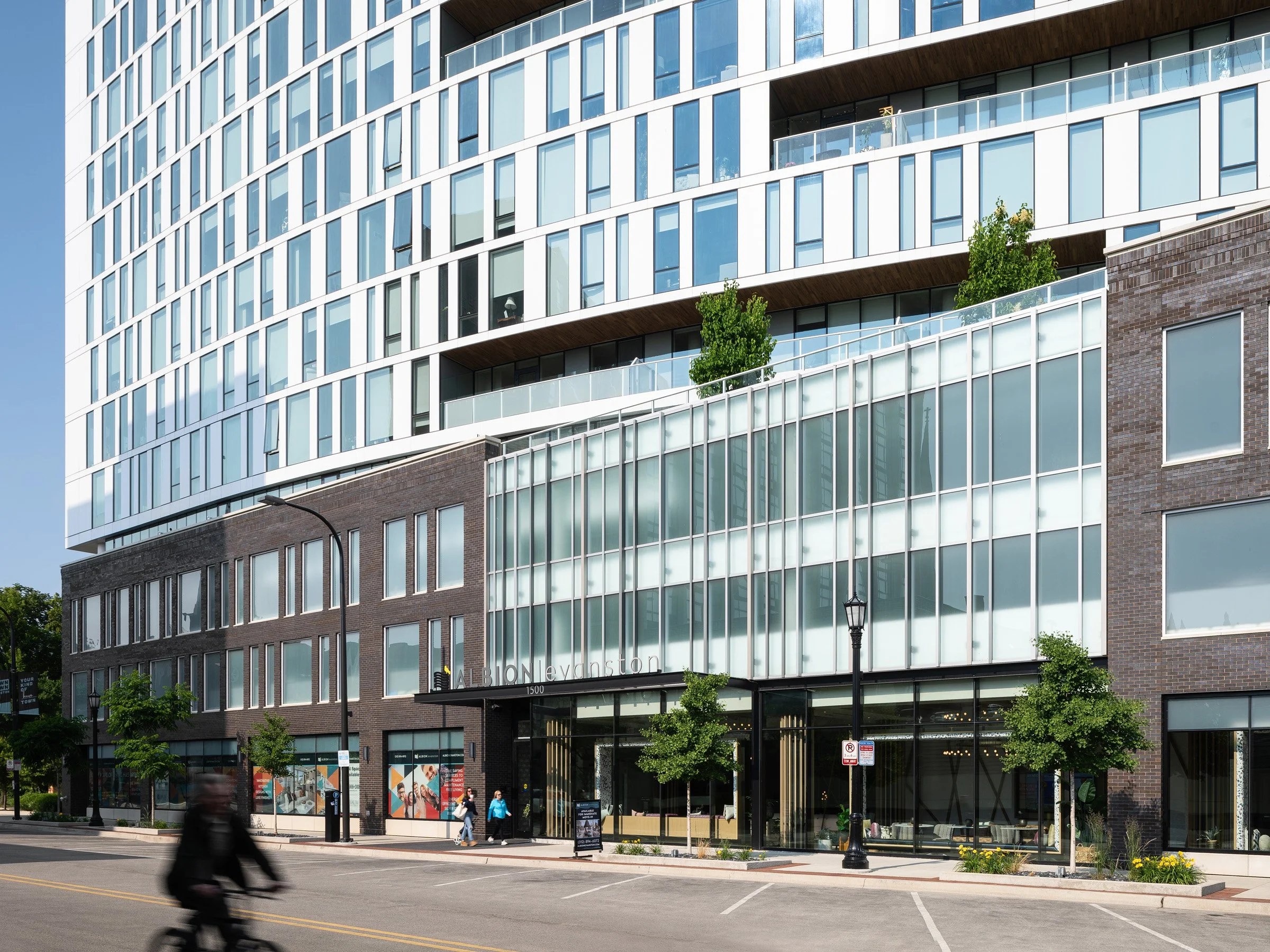 Albion Evanston exterior showing the three-story brick base, ground-floor retail, and translucent glass screen at the entrance, by Hartshorne Plunkard Architecture, Evanston Illinois - architectural photographer Chicago Illinois