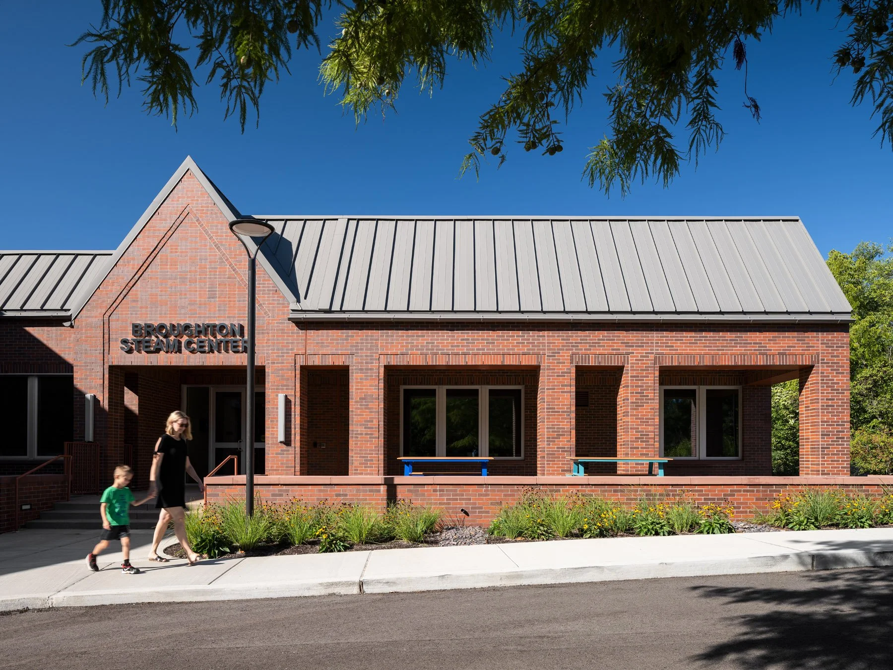 Broughton STEAM Center front brick entrance gable with signage and people walking past, by Christner - architectural photographer St. Louis Missouri