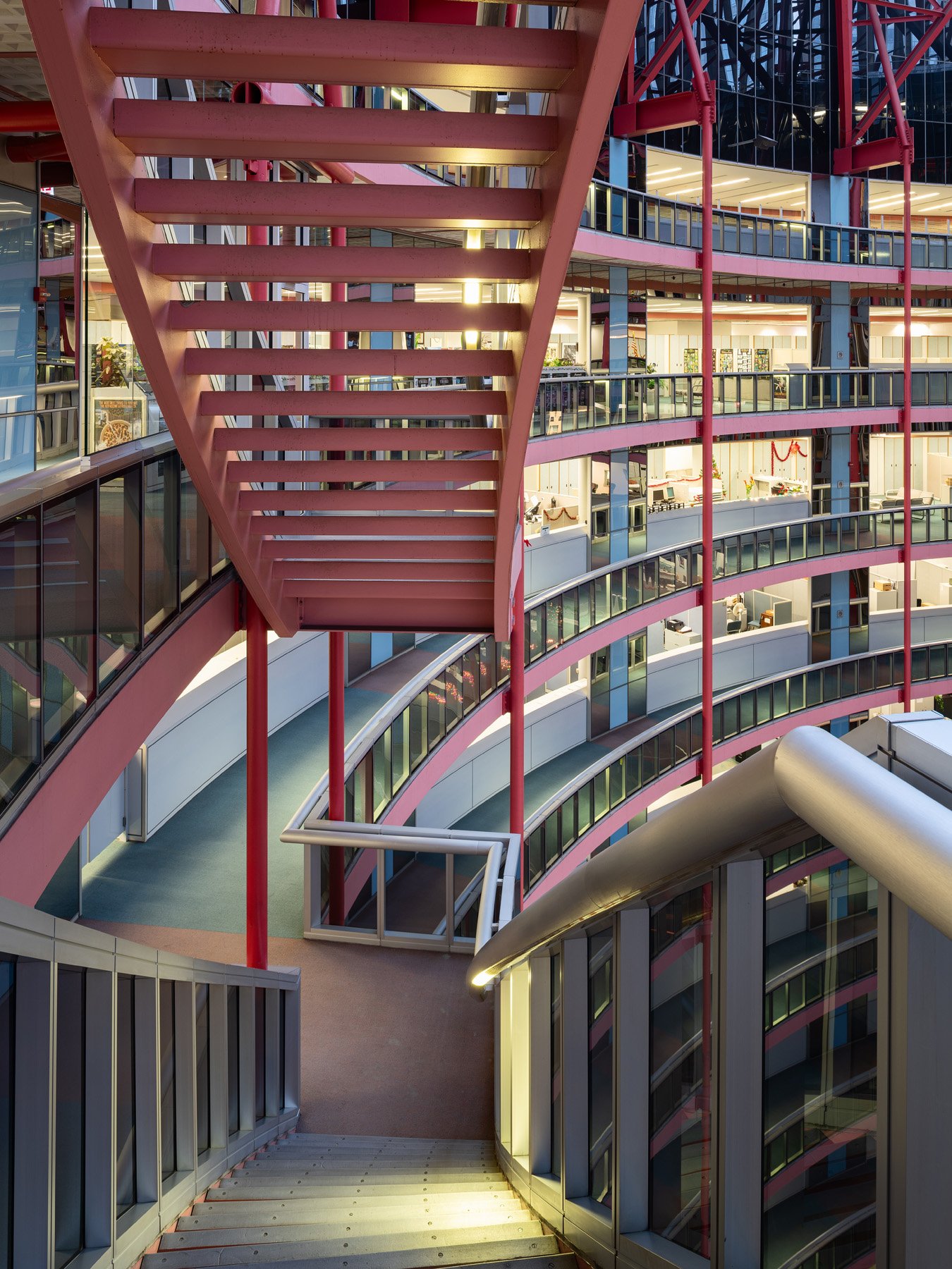 James R. Thompson Center open stair at dusk, salmon underside and lit office tiers behind, Chicago - after hours interior