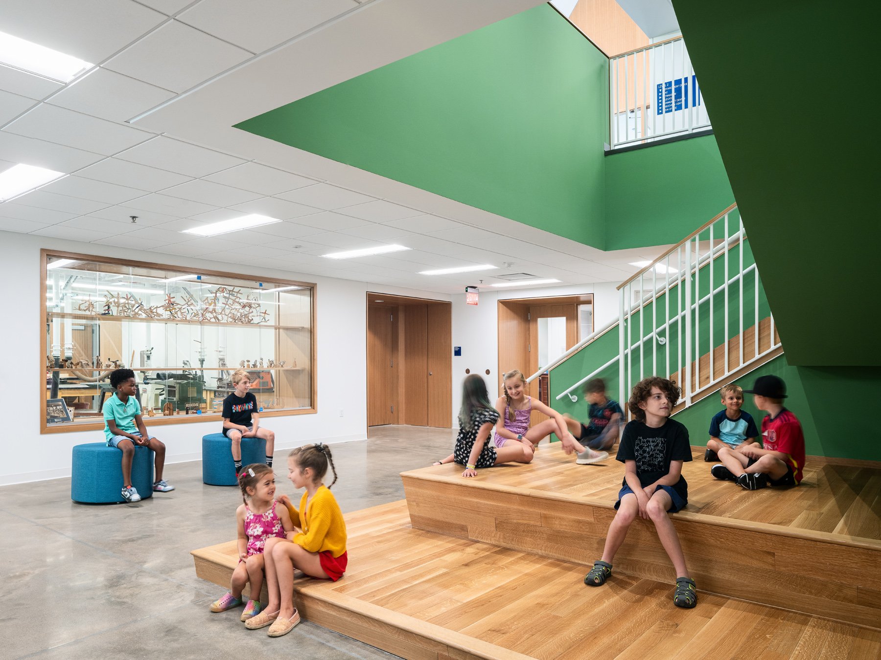 Broughton STEAM Center interior commons with tiered wood seating beside the woodshop, by Christner - architectural photographer St. Louis Missouri
