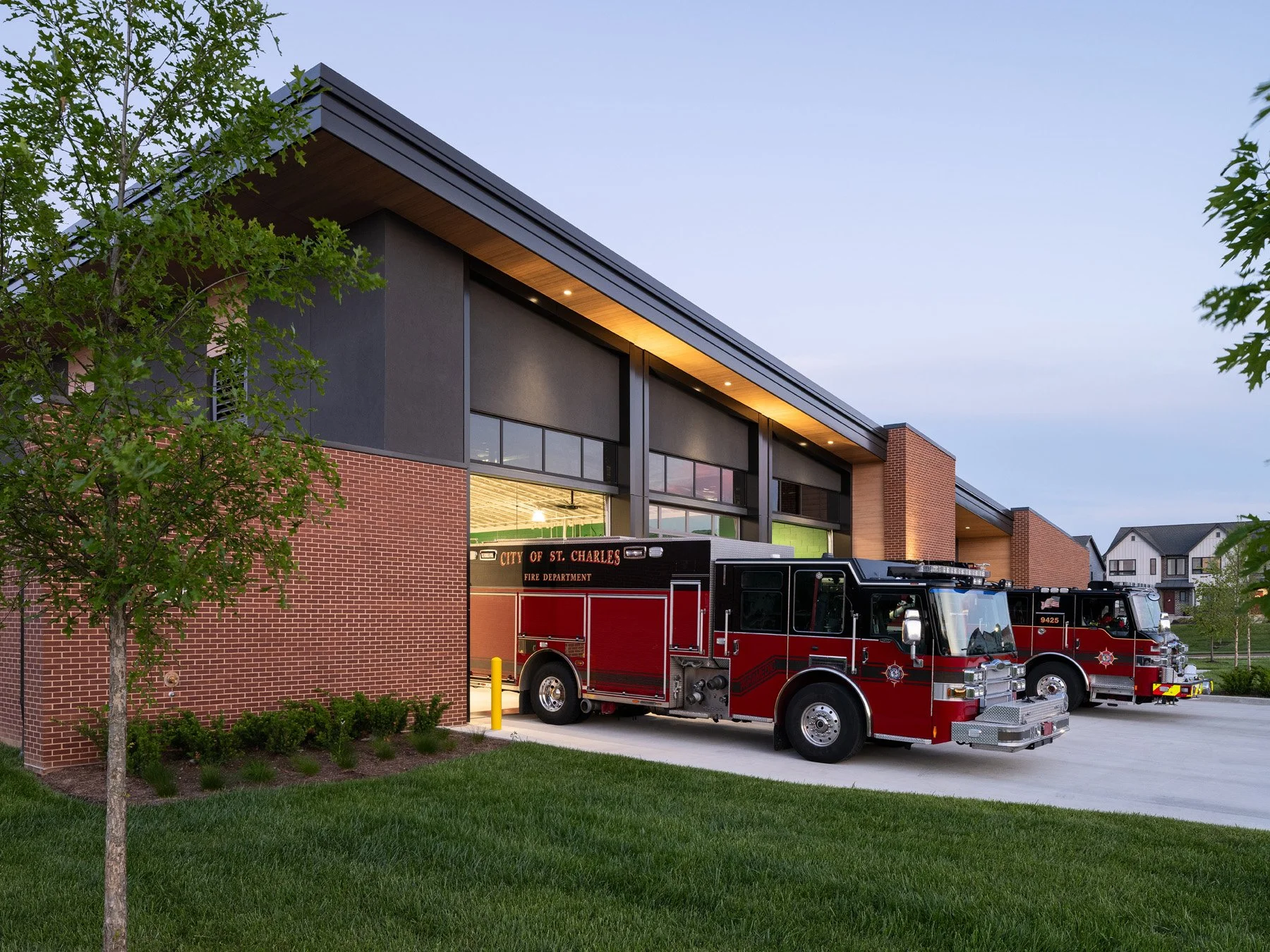 St. Charles fire station dusk side elevation with two parked engines, by JEMA, St. Charles Missouri - architectural photographer St. Louis Missouri
