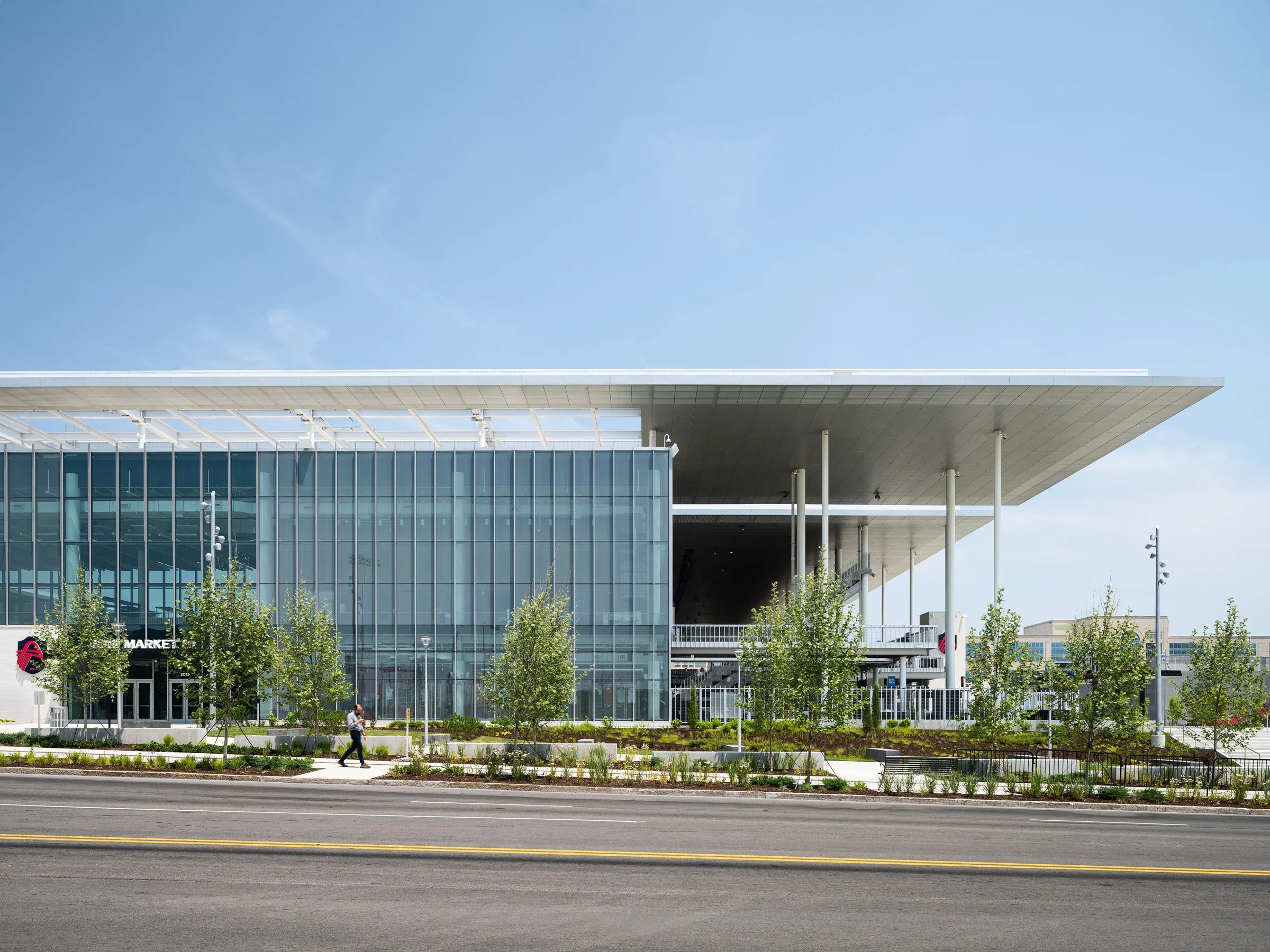 Energizer Park exterior by day showing the glass concourse and the deep cantilevered canopy carried on slender columns, St. Louis CITY SC soccer stadium by HOK and Snow Kreilich, St. Louis Missouri - architectural photographer St. Louis Missouri