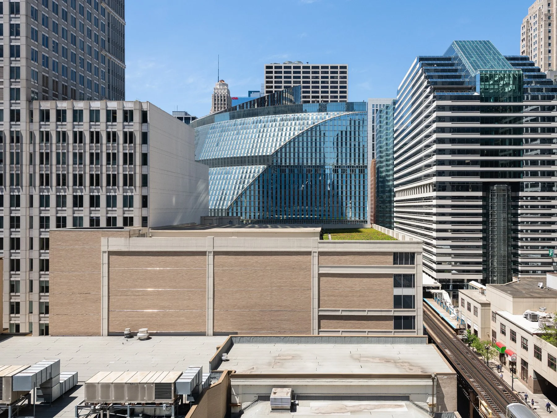 James R. Thompson Center seen across Loop rooftops, the curved blue glass mass among taller towers, Chicago - downtown Loop skyline