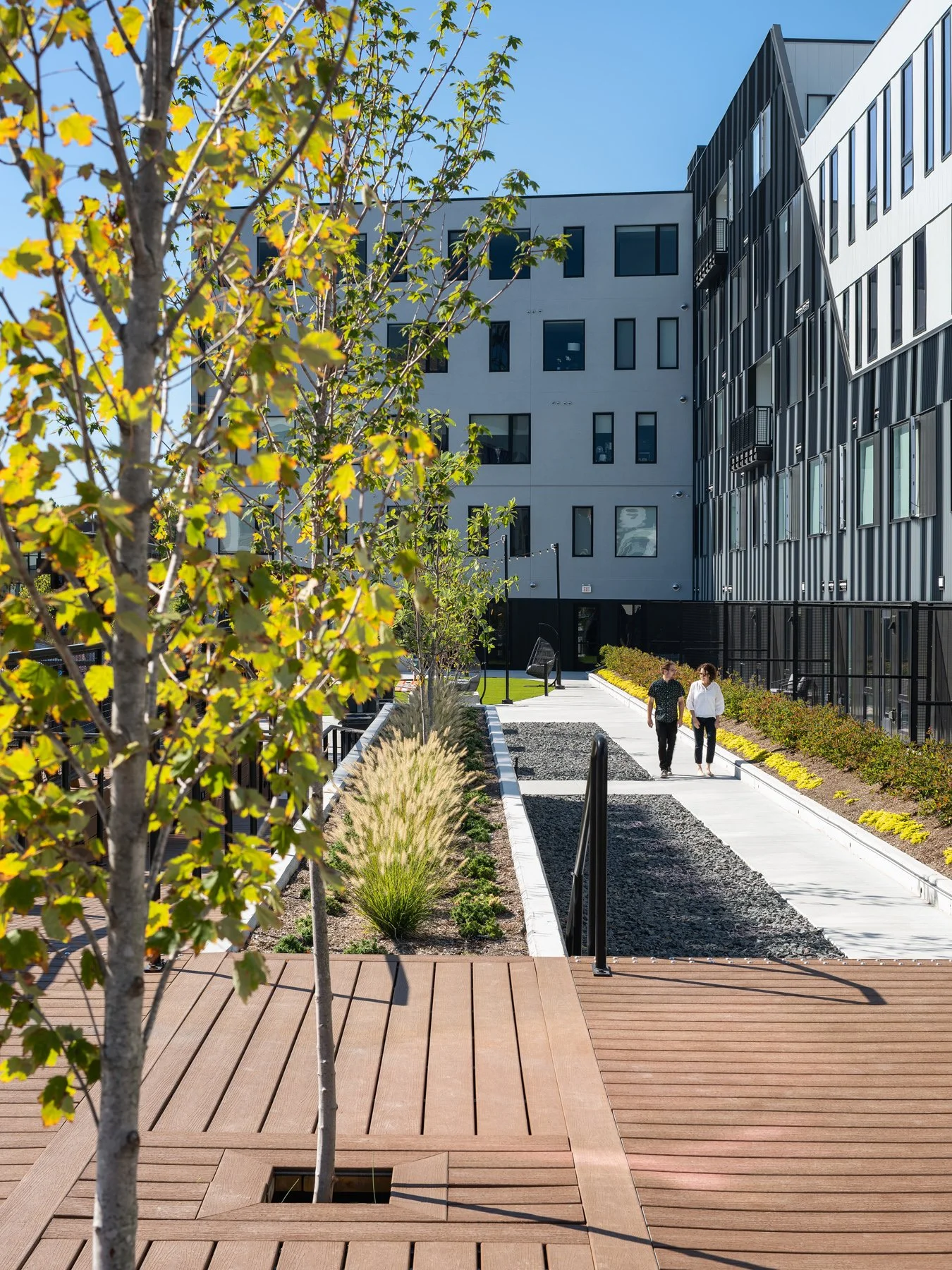 Steelcote Flats amenity deck walkway and planting beds with residents walking, landscape by Arbolope Studio - architectural photographer St. Louis Missouri