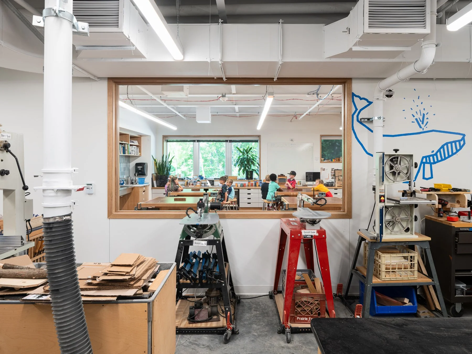 Broughton STEAM Center interior woodshop with band saws and a glass window into a classroom, by Christner - architectural photographer St. Louis Missouri
