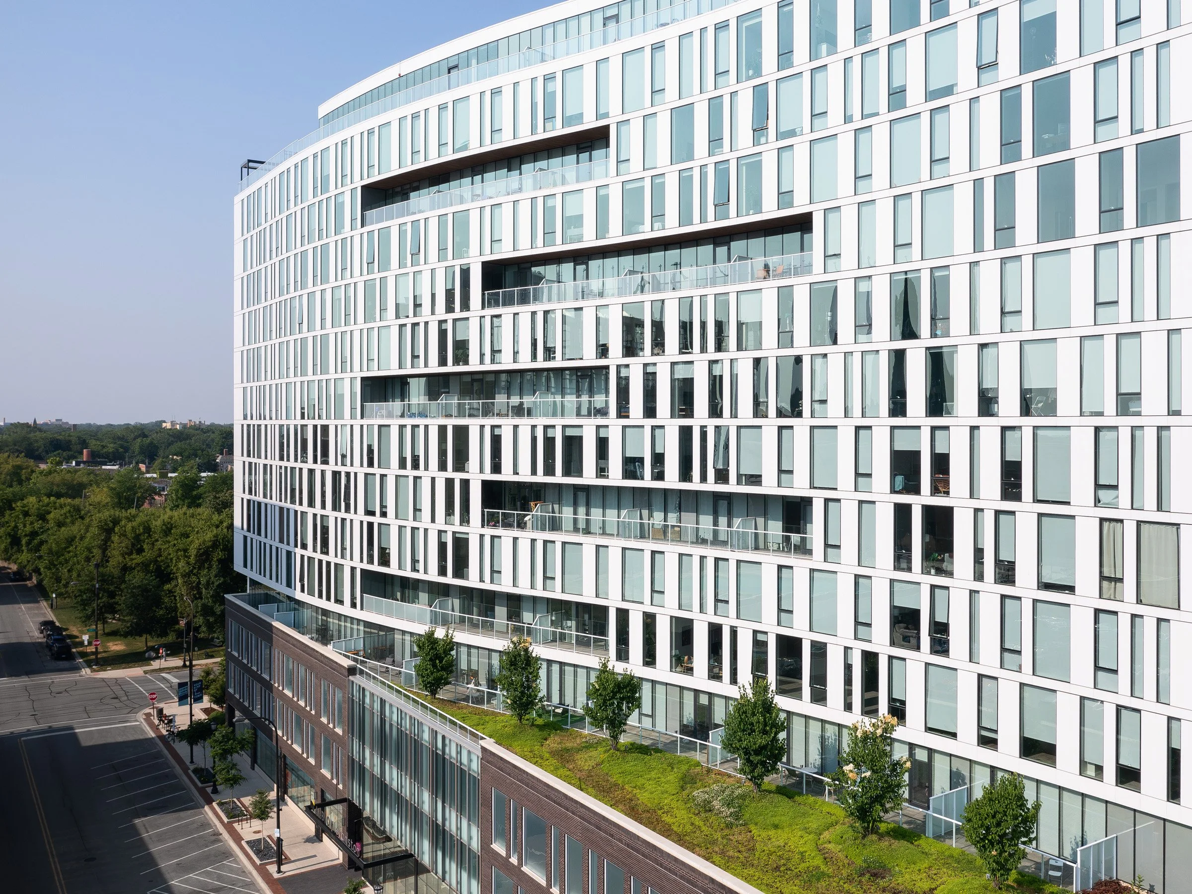 Albion Evanston exterior elevated view of the curving facade and balconies above a planted green roof terrace, by Hartshorne Plunkard Architecture, Evanston Illinois - architectural photographer Chicago Illinois