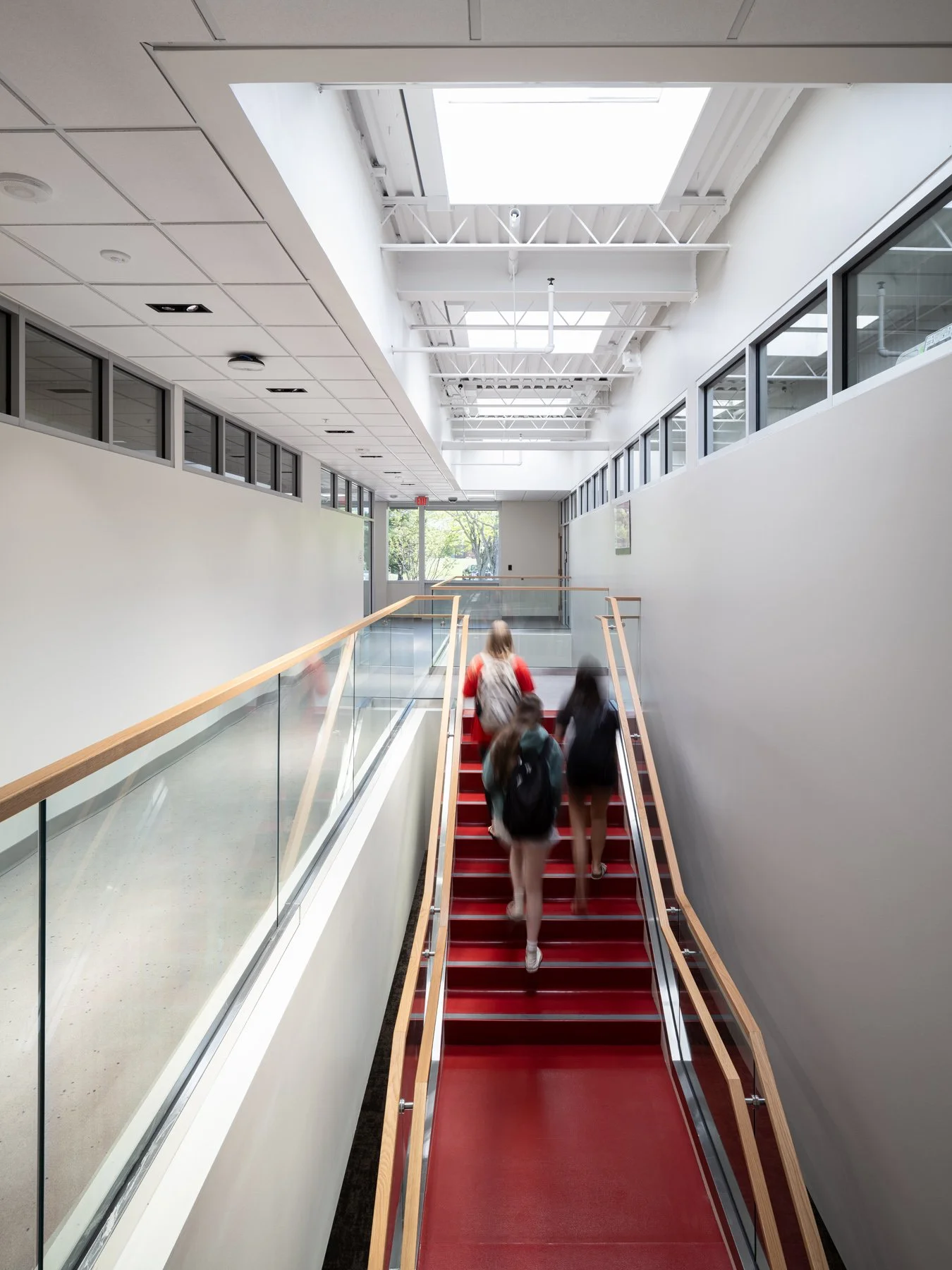 SIUE Health Sciences interior red stair under a skylit bridge with students by Christner, Edwardsville Illinois - architectural photographer St. Louis