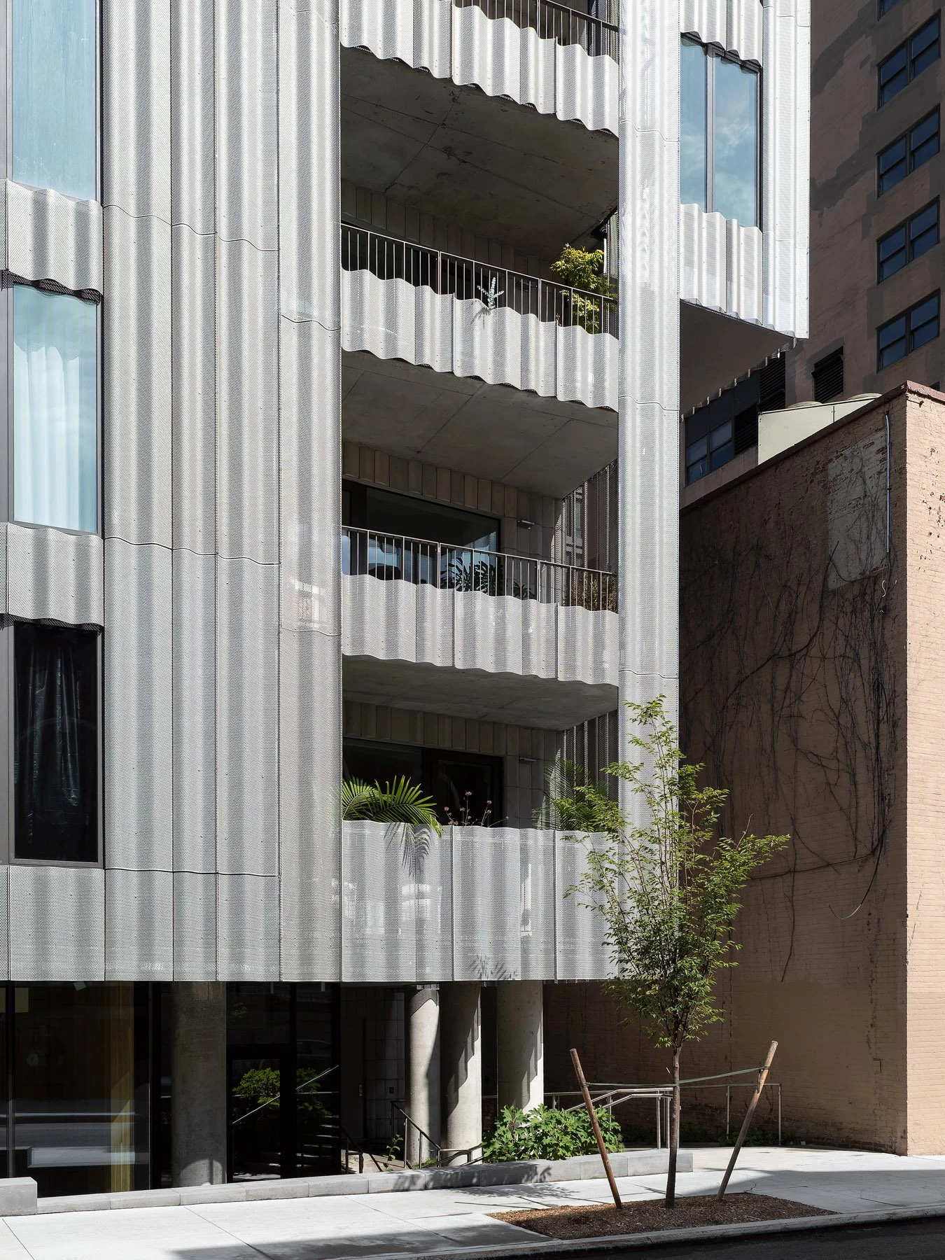 9 Chapel side elevation showing stacked open balconies, scalloped aluminum fins, and ground-level entry planting, by SO–IL - architectural photographer New York