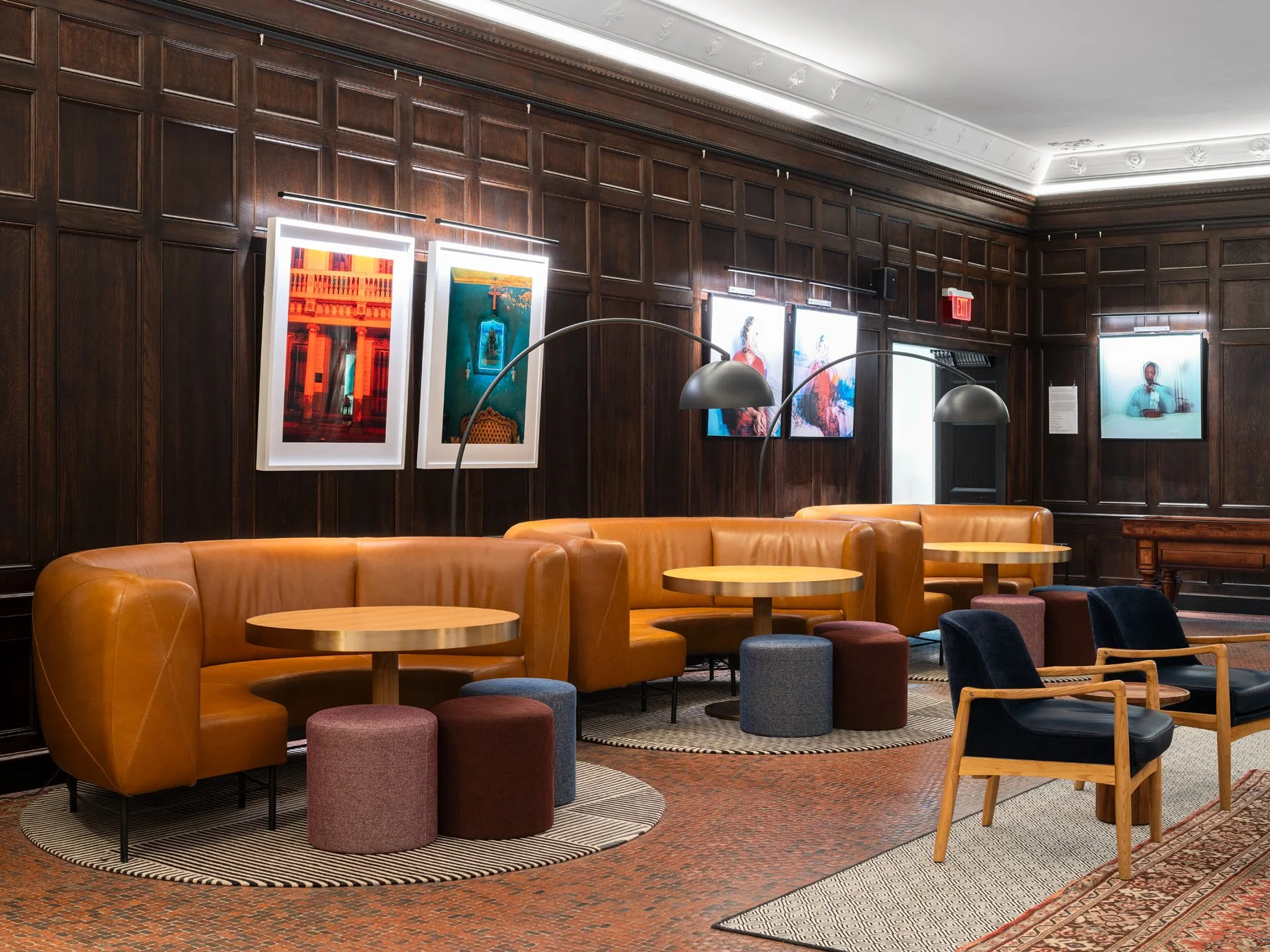 21c Museum Hotel interior lounge with curved tan leather banquettes set against dark wood paneling hung with contemporary photography, by Perfido Weiskopf Wagstaff + Goettel and Hufft - architectural photographer St. Louis Missouri