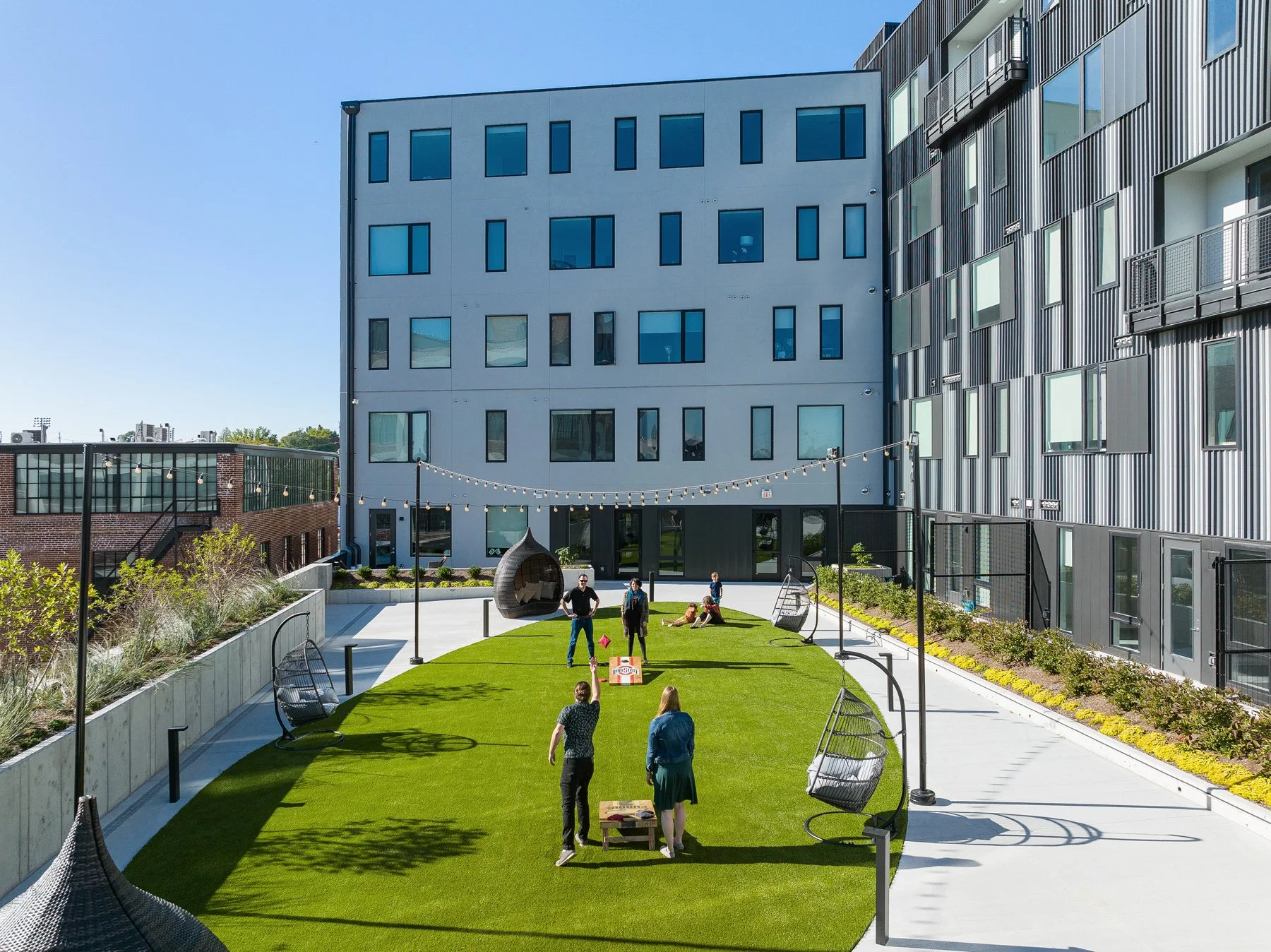 Steelcote Flats courtyard lawn and string lights with residents at play, by Trivers - architectural photographer St. Louis Missouri