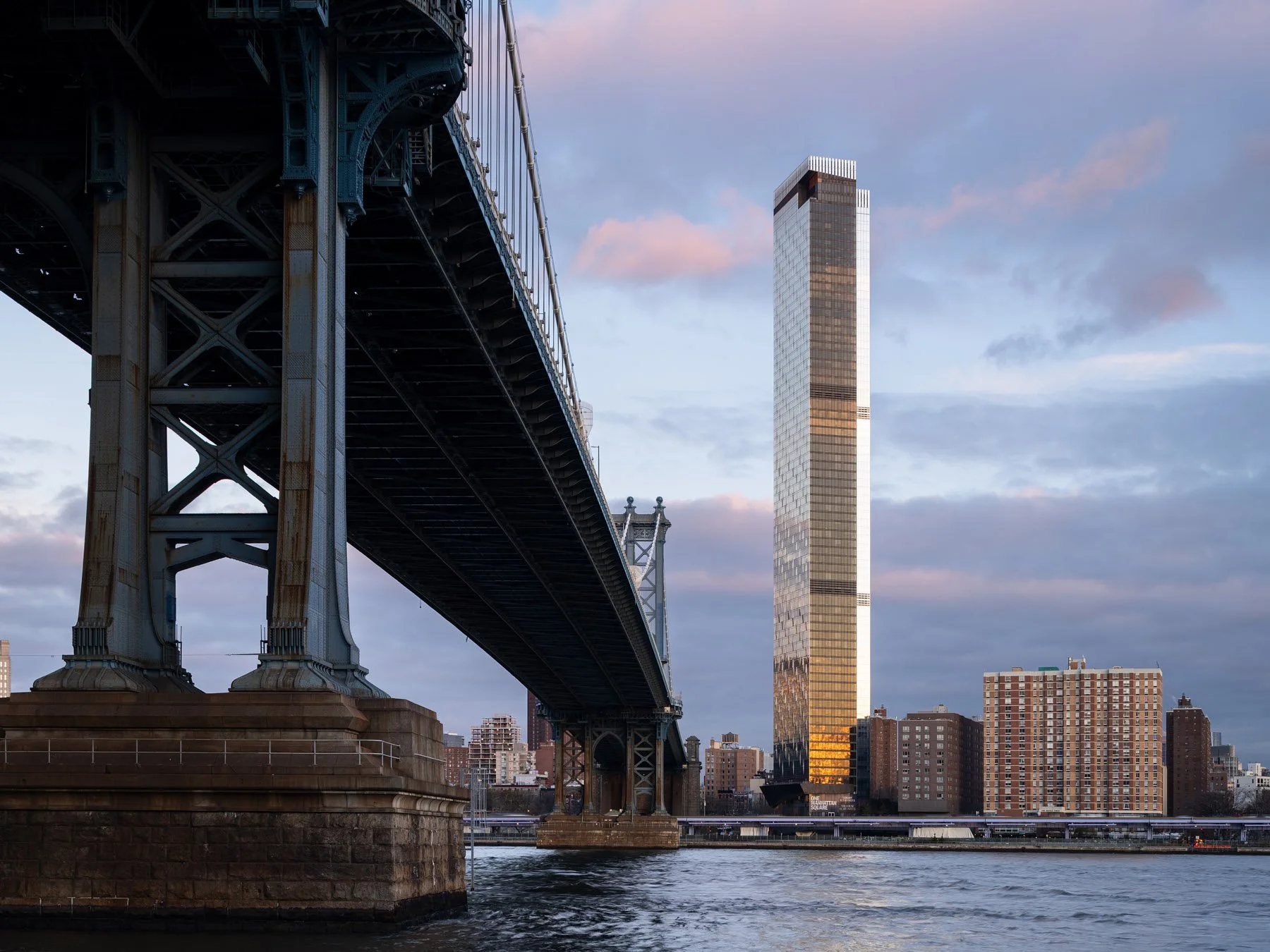 One Manhattan Square tower seen past the Manhattan Bridge at dusk, by Adamson Associates, New York - architectural photographer New York