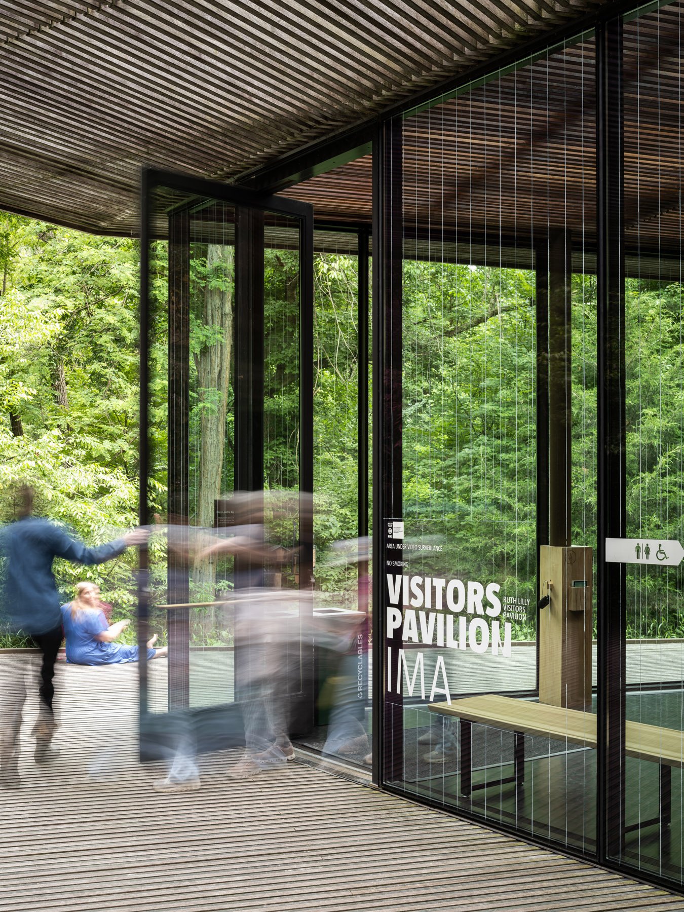 Ruth Lilly Visitors Pavilion entry doors with motion-blurred figures passing through, by Marlon Blackwell Architects, Indianapolis Indiana - architectural photographer