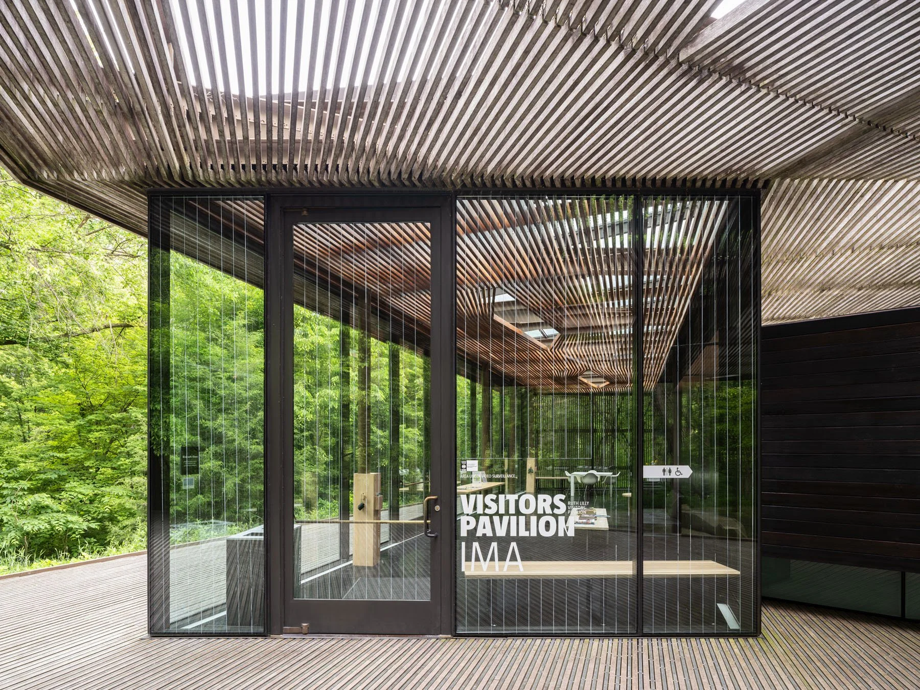 Ruth Lilly Visitors Pavilion glazed entry facade with warm wood slat ceiling viewed from covered deck, by Marlon Blackwell Architects, Indianapolis Indiana - architectural photographer