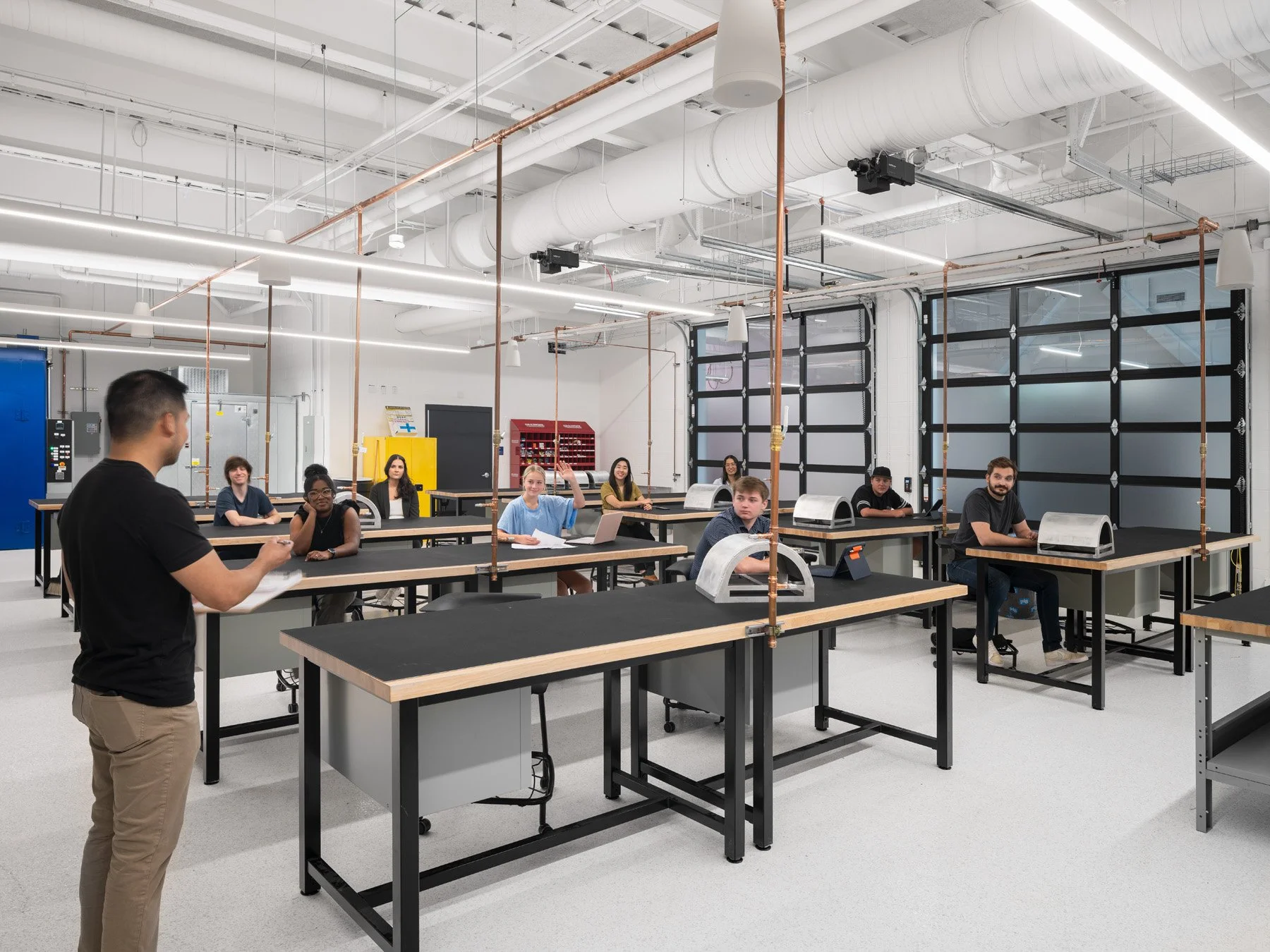 Higher education architectural photography of a college class, a student raising her hand at workbenches - architectural photographer St. Louis