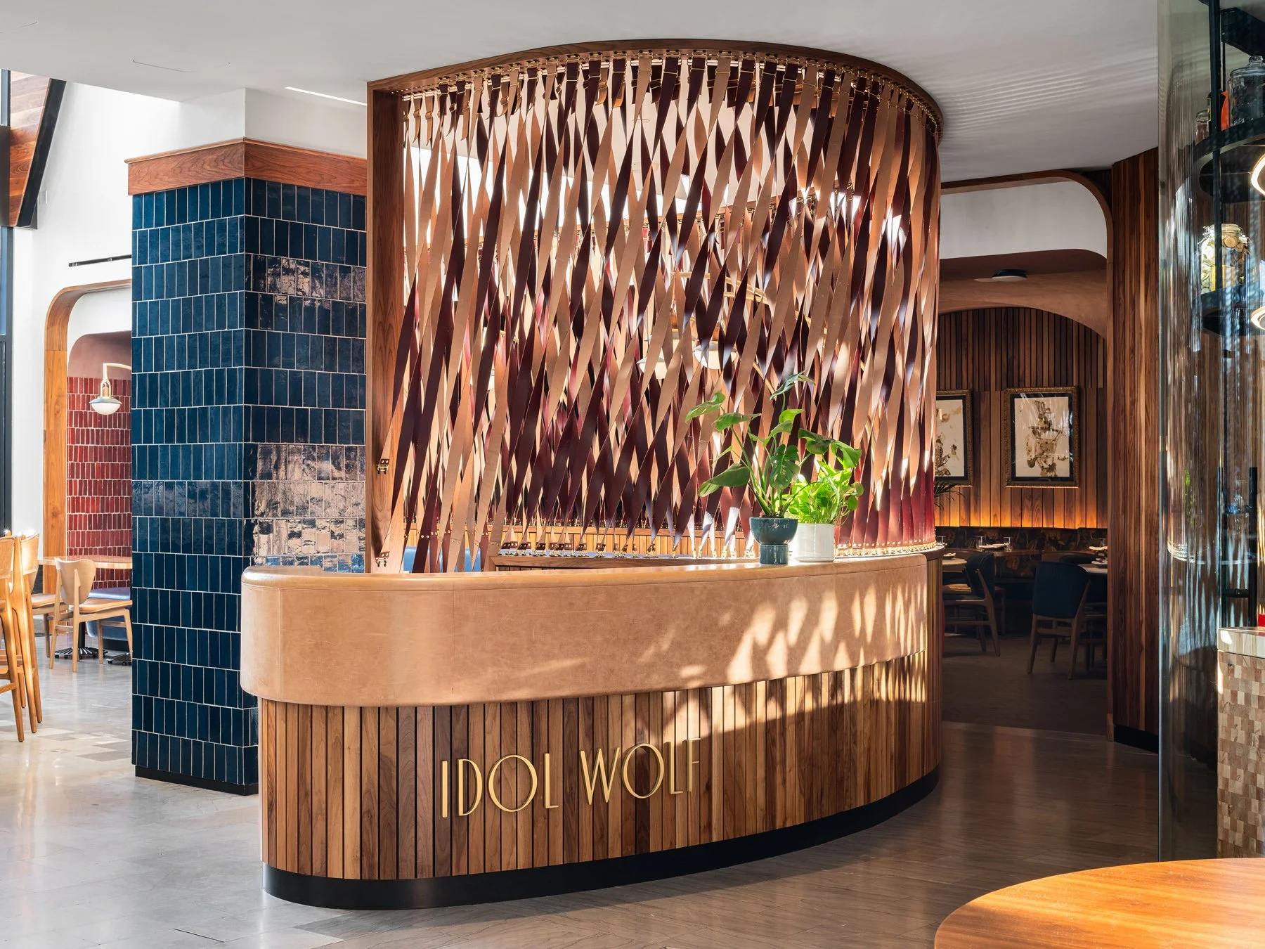 Idol Wolf restaurant interior host stand with brass lettering backed by a woven copper ribbon screen and blue tile column, at the 21c Museum Hotel by Perfido Weiskopf Wagstaff + Goettel and Hufft - architectural photographer St. Louis Missouri