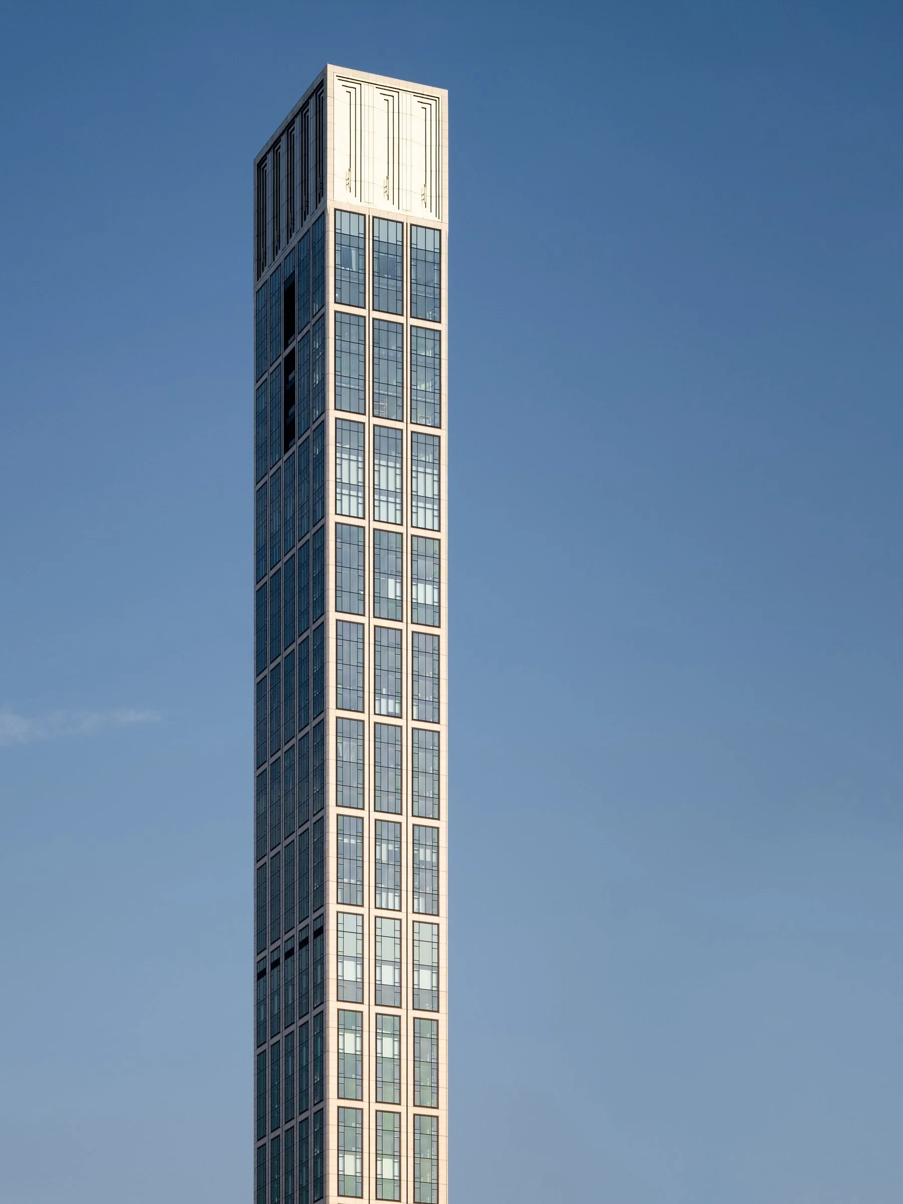Sutton Tower crown detail against a clear sky showing the limestone facade and the light-yellow metallic top with angular planes, by Thomas Juul-Hansen, New York New York - architectural photographer