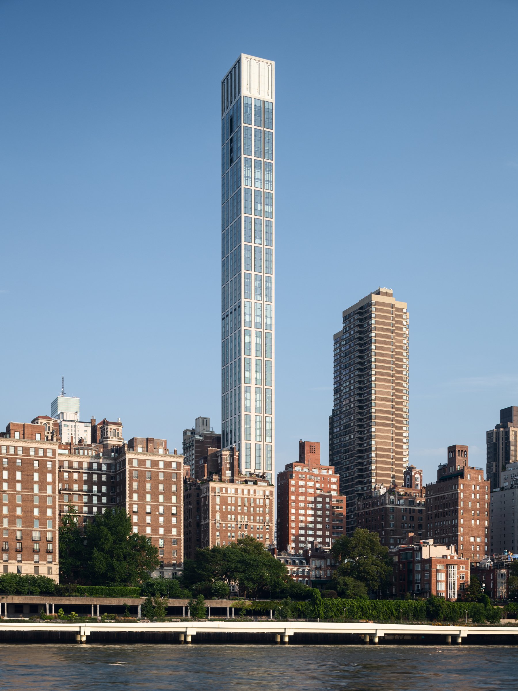 Sutton Tower by day from across the East River, the slim residential skyscraper rising above the low-rise pre-war buildings of Sutton Place, by Thomas Juul-Hansen, New York New York - architectural photographer