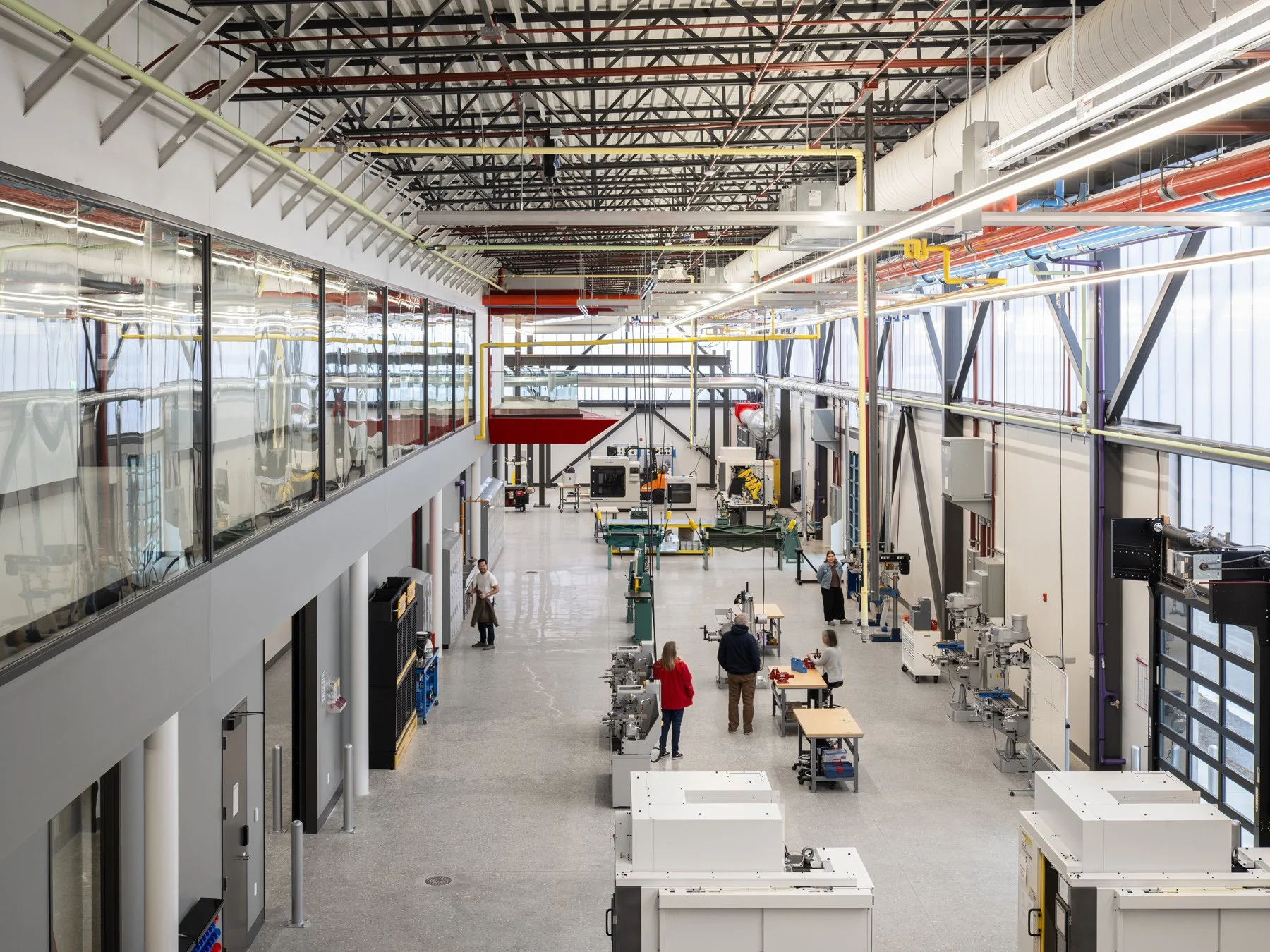 Regional Workforce Innovation Center machining lab seen from above showing rows of lathes and mills under exposed steel trusses and color-coded piping, Wentzville, Missouri, by JEMA - architectural photographer St. Louis Missouri