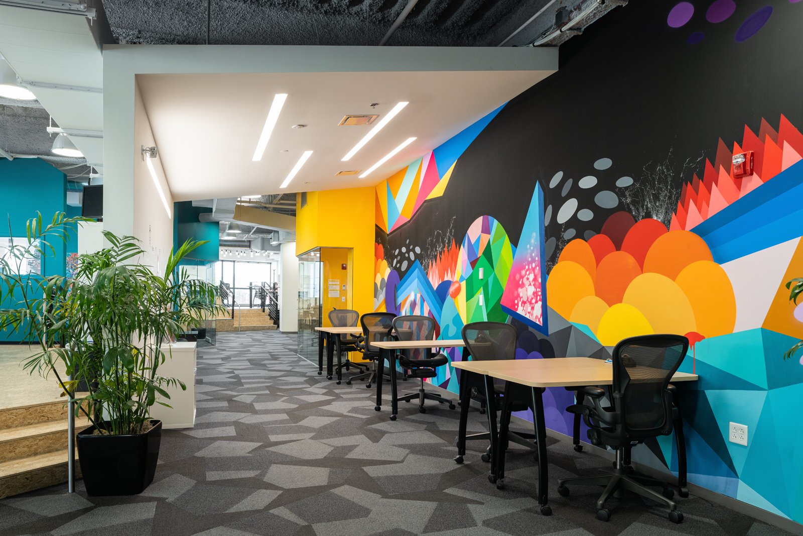 4220 Duncan interior coworking space with geometric wall mural and workstations, by HOK - architectural photographer St. Louis Missouri