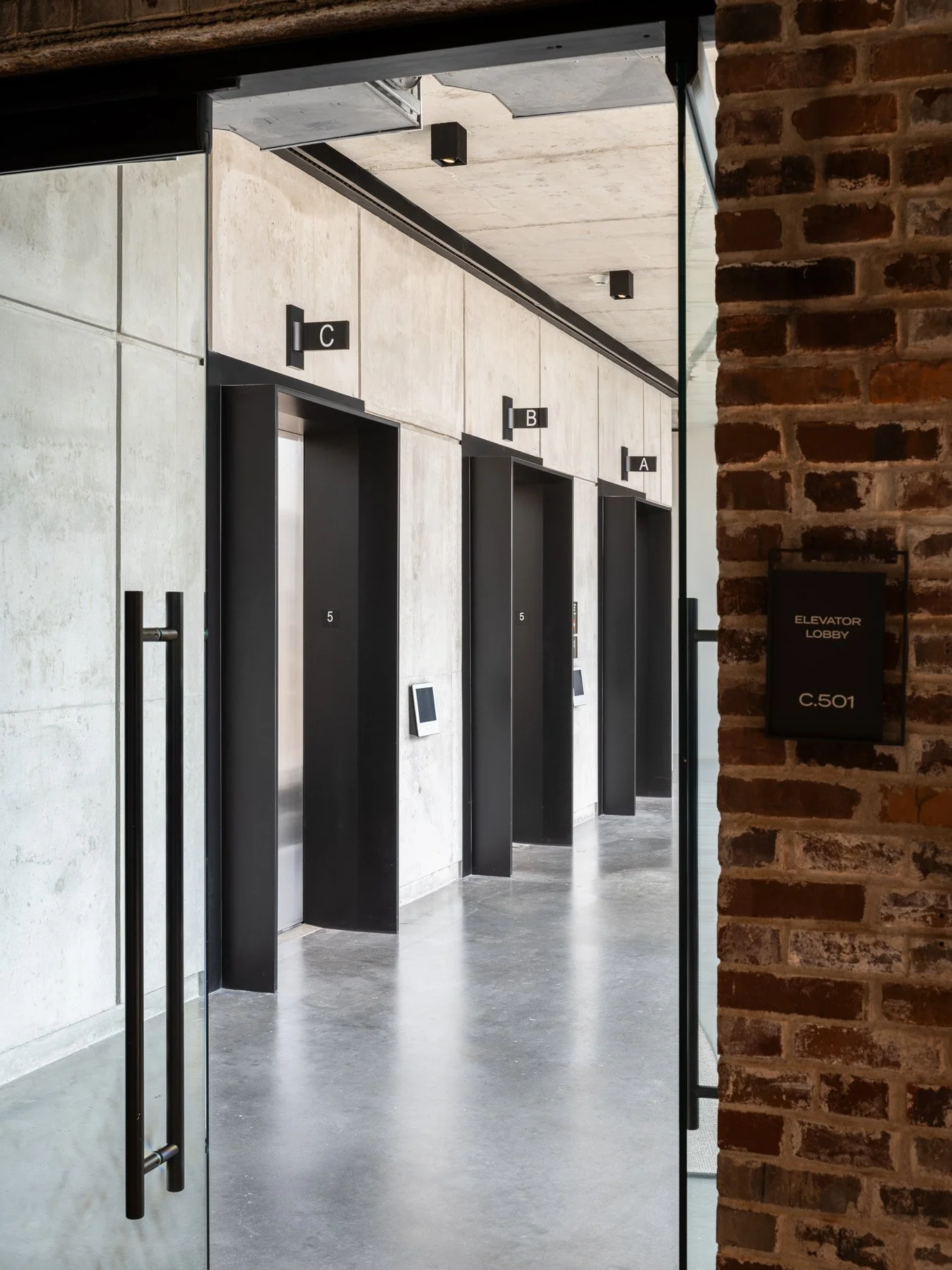 Neuhoff District elevator lobby with concrete walls and exposed brick by Smith Gee Studio - architectural photographer Nashville Tennessee