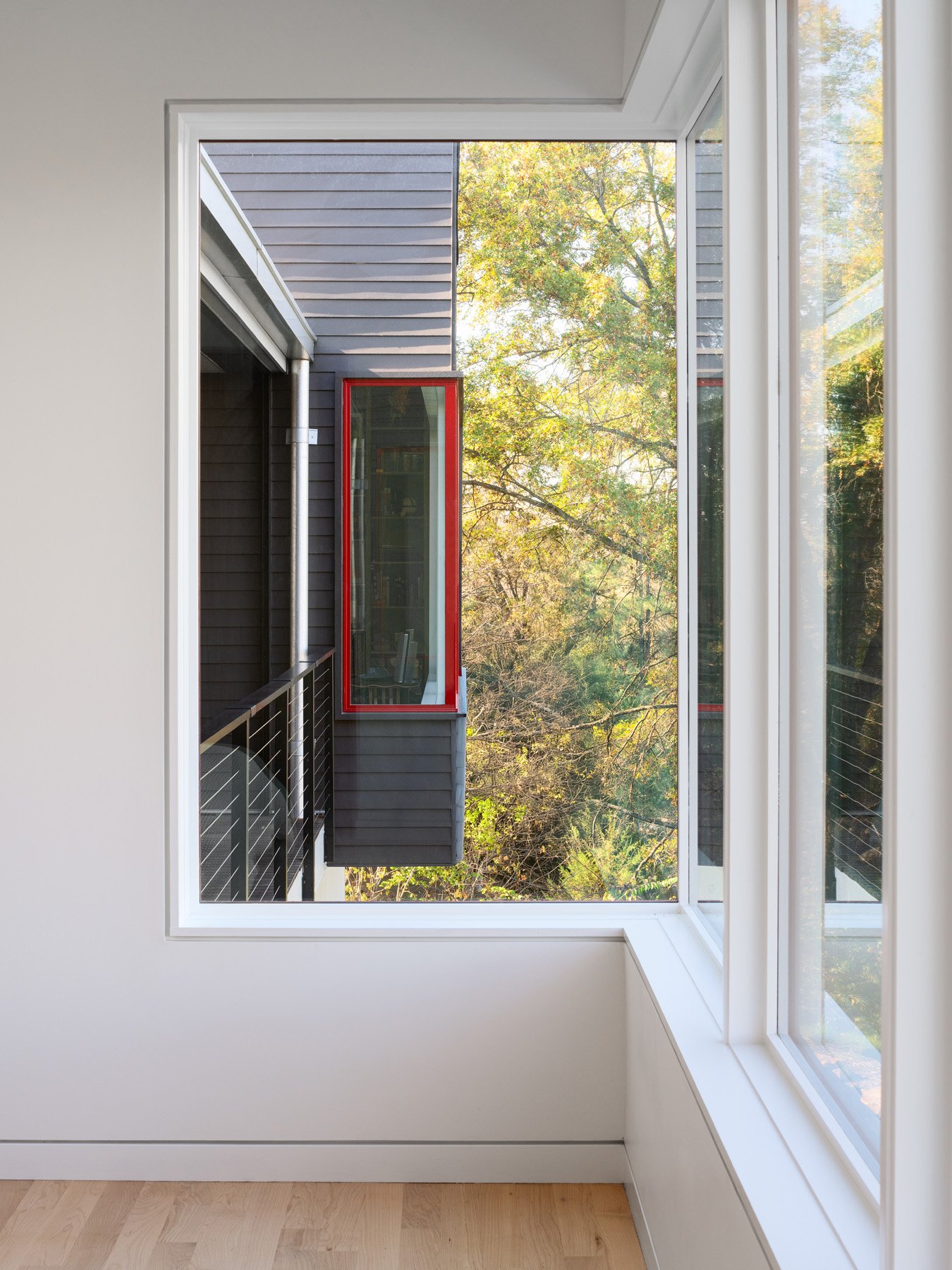 Monty Residence interior window framing a red trimmed window and deck in the trees, by Studio Lark - architectural photographer St. Louis Missouri