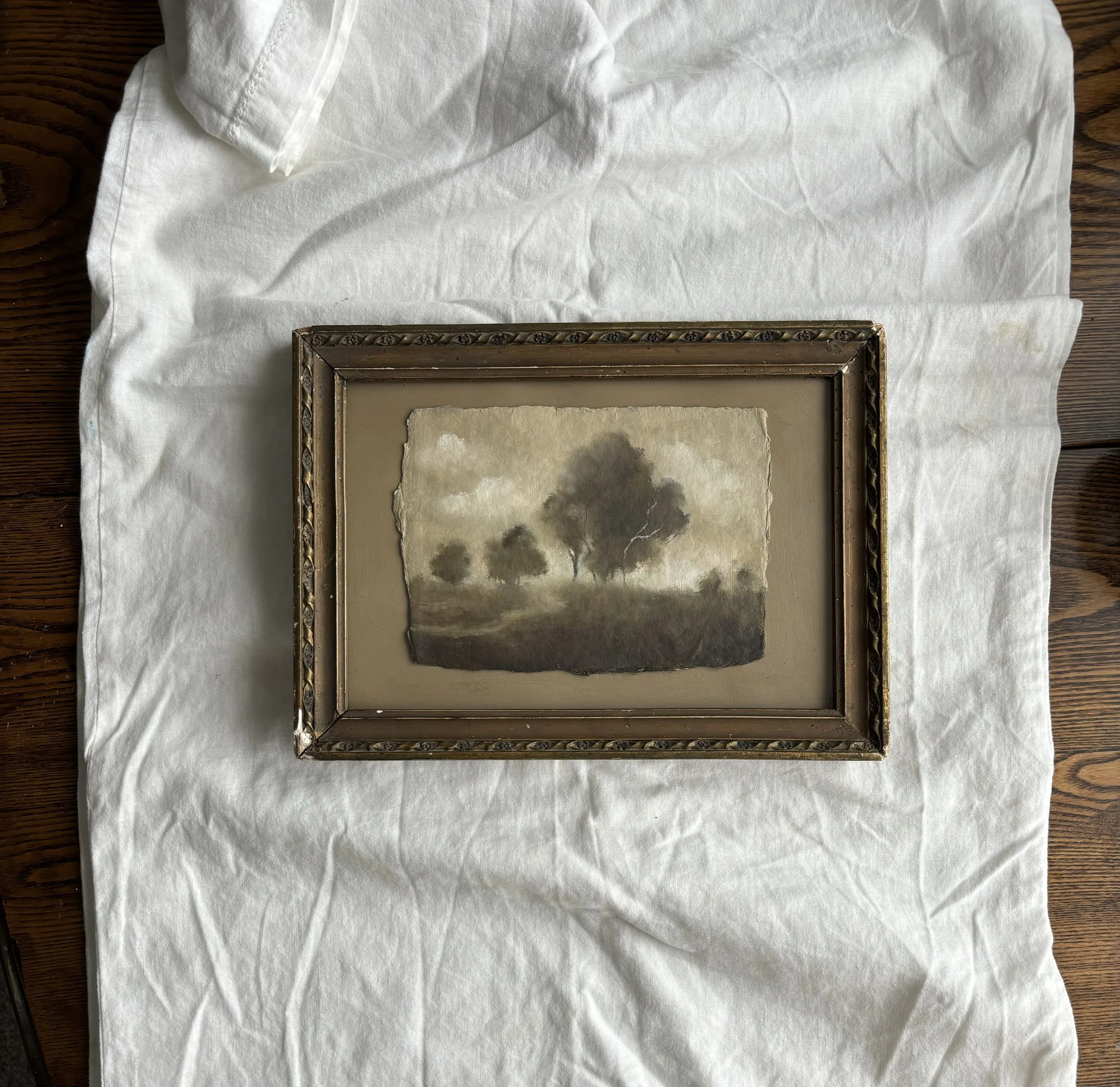 Vintage framed landscape painting with trees on white fabric background