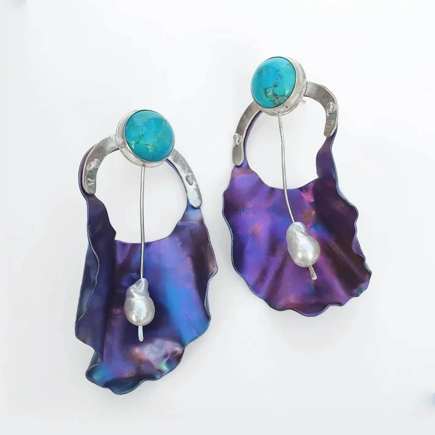 Introducing the Martina stud earrings, Malki&rsquo;s newest addition.

A handmade tribute to the rare and graceful Gilboa Iris, these sculptural studs feature rippling anodised titanium petals, a vivid turquoise cabochon, and a soft cultured freshwat