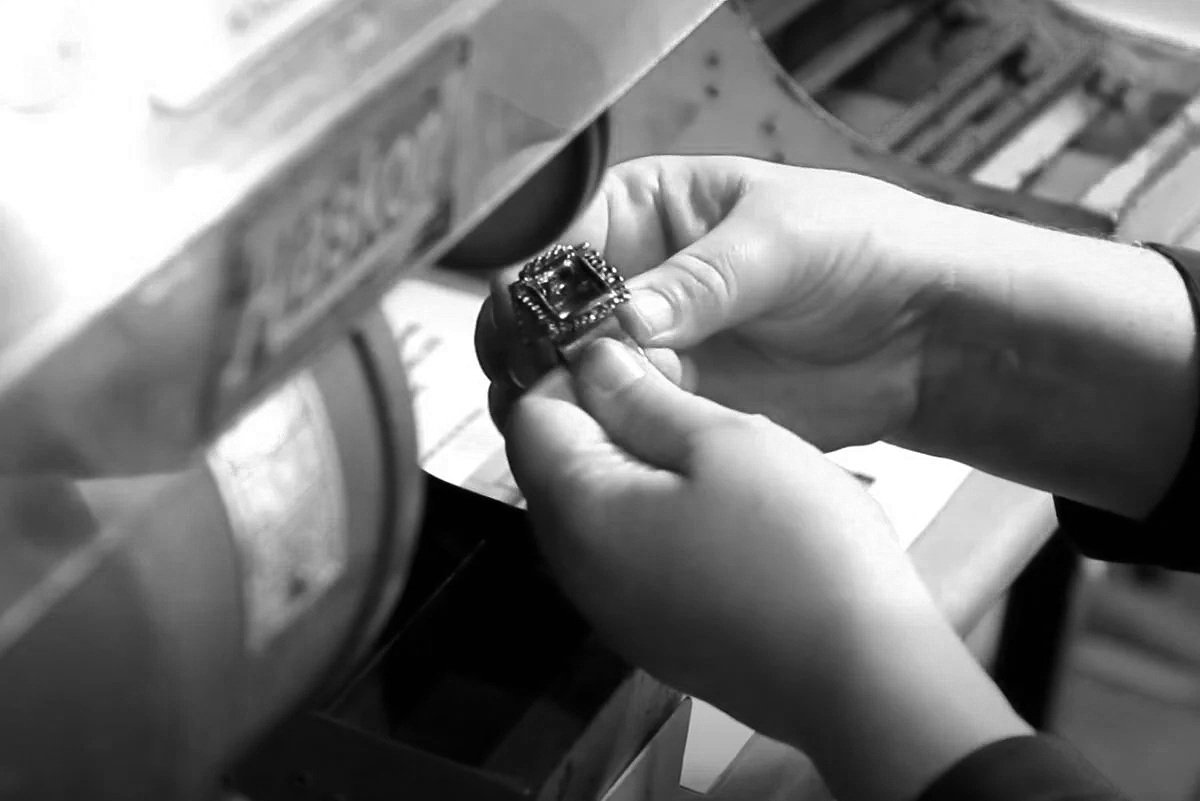 Black and white image showing a jeweller using the polishing wheel