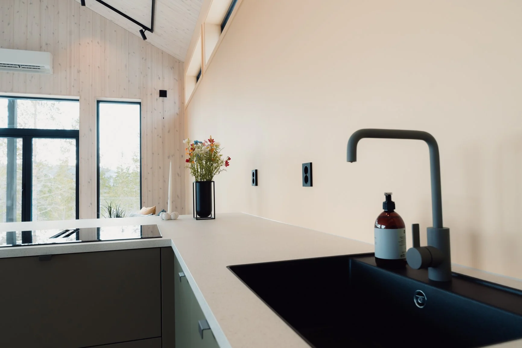 Gipsvegg langs kjøkkenbenken i fargen cheerful peach og smale vindu ovenfor som skjermer innsyn