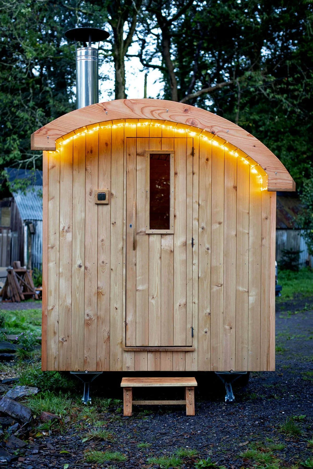 Jamesway sauna door with fairy lights under the eaves taken at dusk