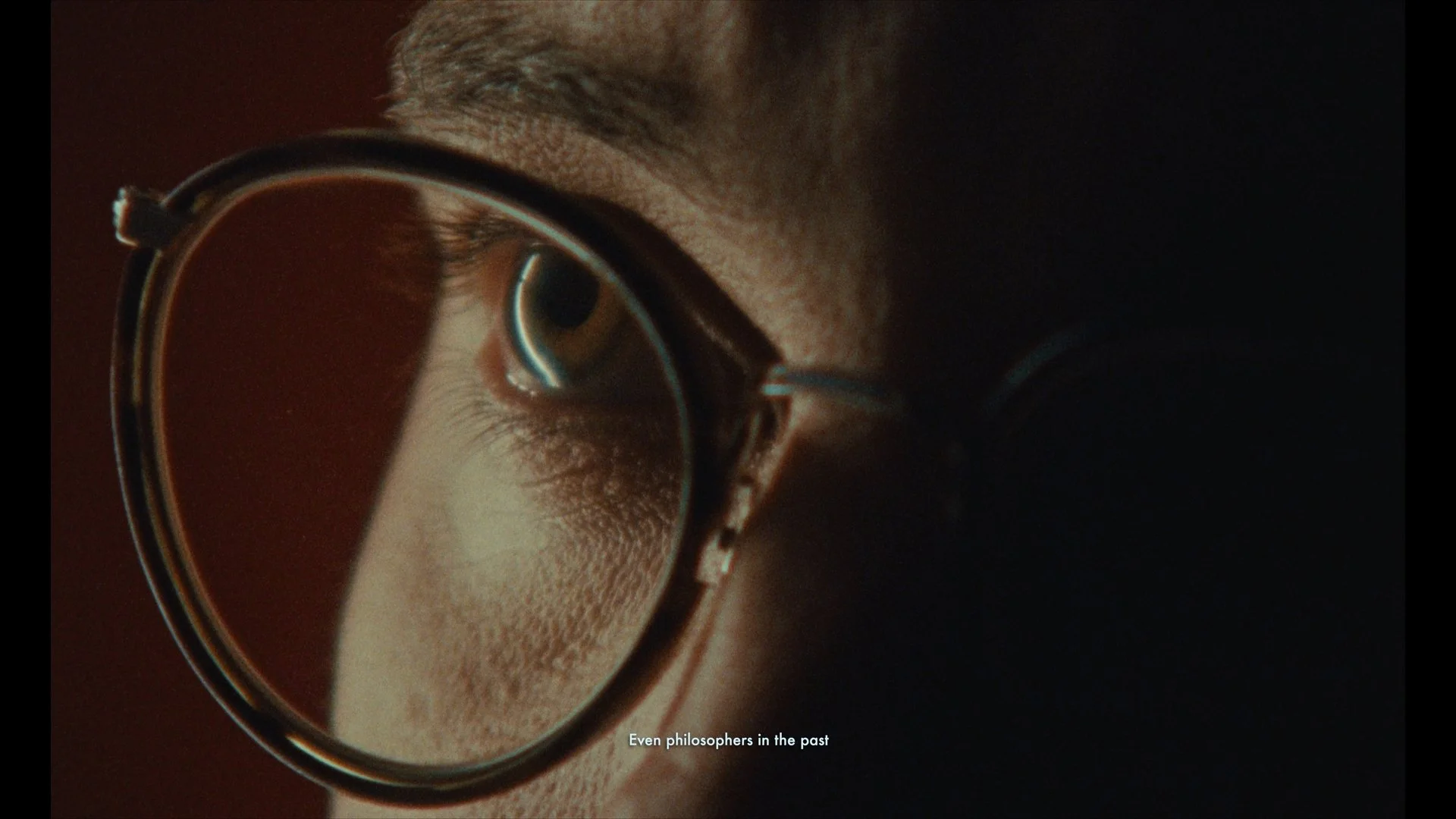 Close-up of a person's face with glasses, showing the eye reflected in the lens, with the caption 'Even philosophers in the past'.
